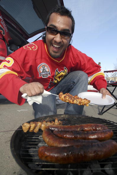 CALGARY, ALBERTA - APRIL 21:  Calgary Flames fan Nikzad Kassam barbeques up some chicken and sausages for his friends during the pre-game party in the parking lot of the Pengrowth Saddledome before the Flames take on the Anaheim Mighty Ducks in Game 1 of