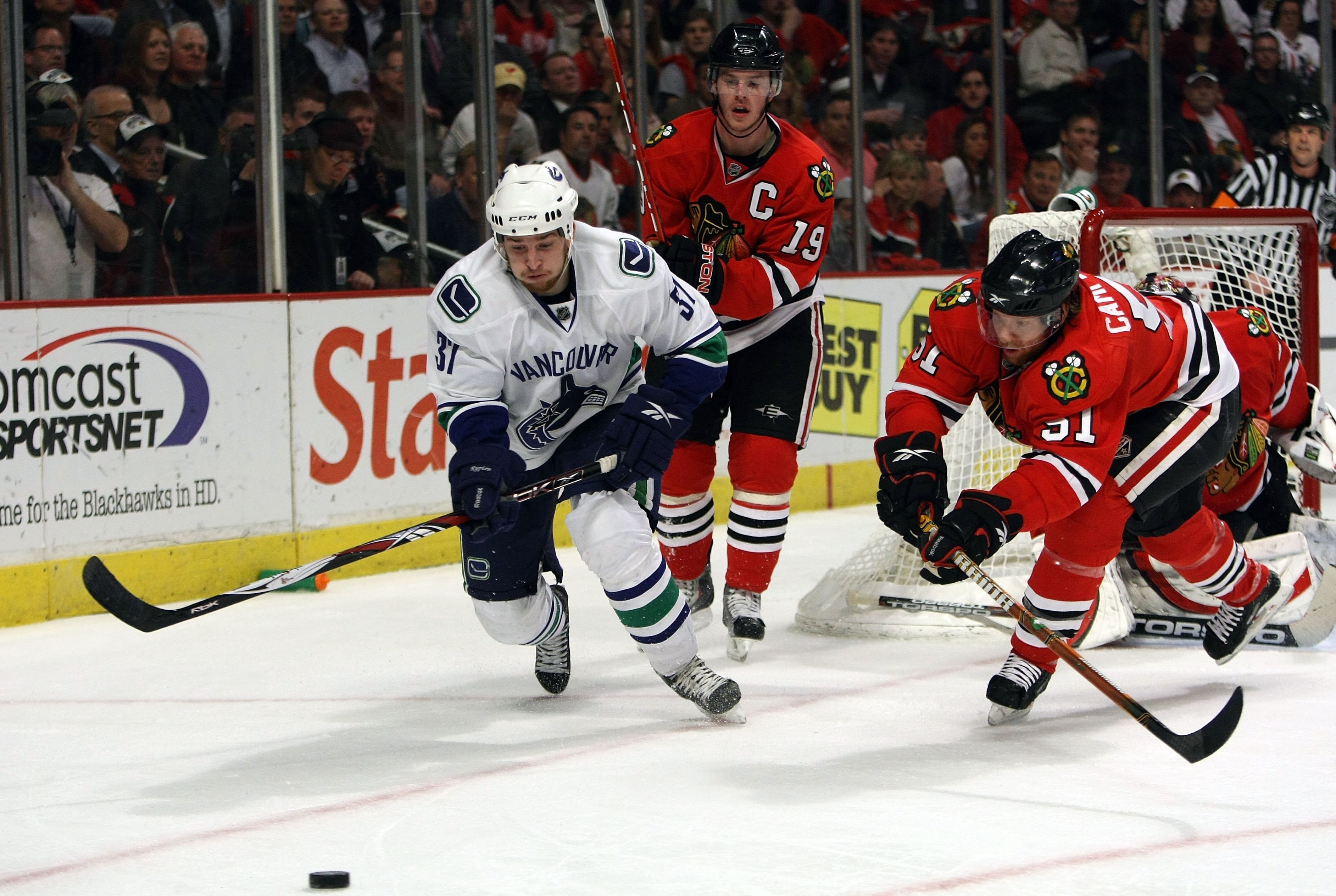 CHICAGO - MAY 11:  Rick Rypien #37 of the Vancouver Canucks attempts to control the puck against Brian Campbell #51 and Jonathan Toews #19 of the Chicago Blackhawks during Game Six of the Western Conference Semifinal Round of the 2009 Stanley Cup Playoffs