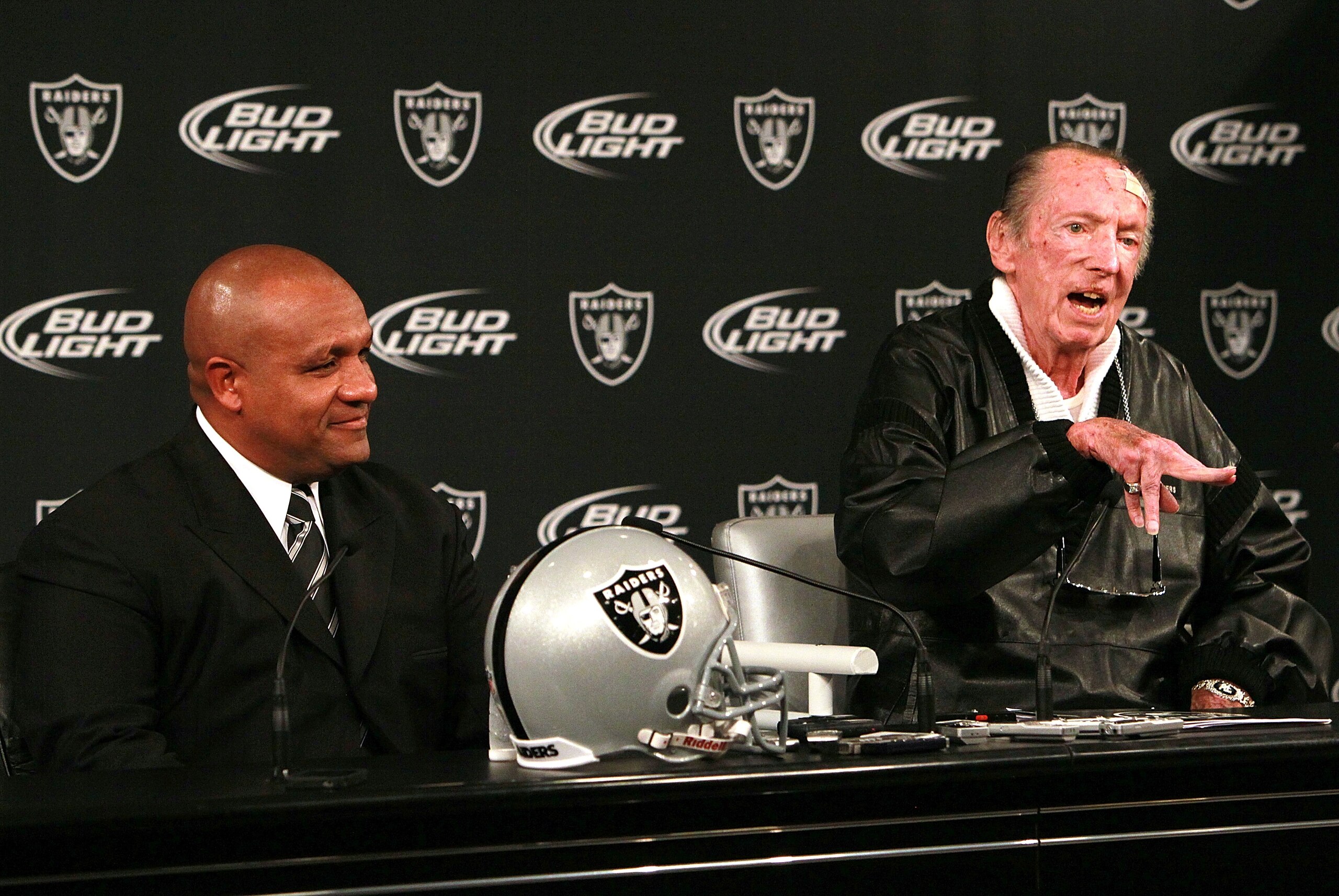 ALAMEDA, CA - JANUARY 18:  New Oakland Raiders coach Hue Jackson (L) looks on as Raiders owner Al Davis (R) speaks to reporters after introducing Jackson as the new head coach of the Oakland Raiders on January 18, 2011 in Alameda, California.  Hue Jackson