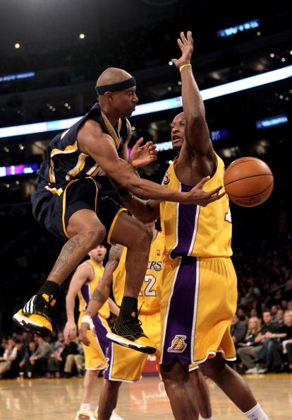 LOS ANGELES, CA - MARCH 02:  T.J. Ford #5 of the Indiana Pacers passes around Lamar Odom #7 of the Los Angeles Lakers on March 2, 2010 at Staples Center in Los Angeles, California. The Lakers won 122-99.  NOTE TO USER: User expressly acknowledges and agre