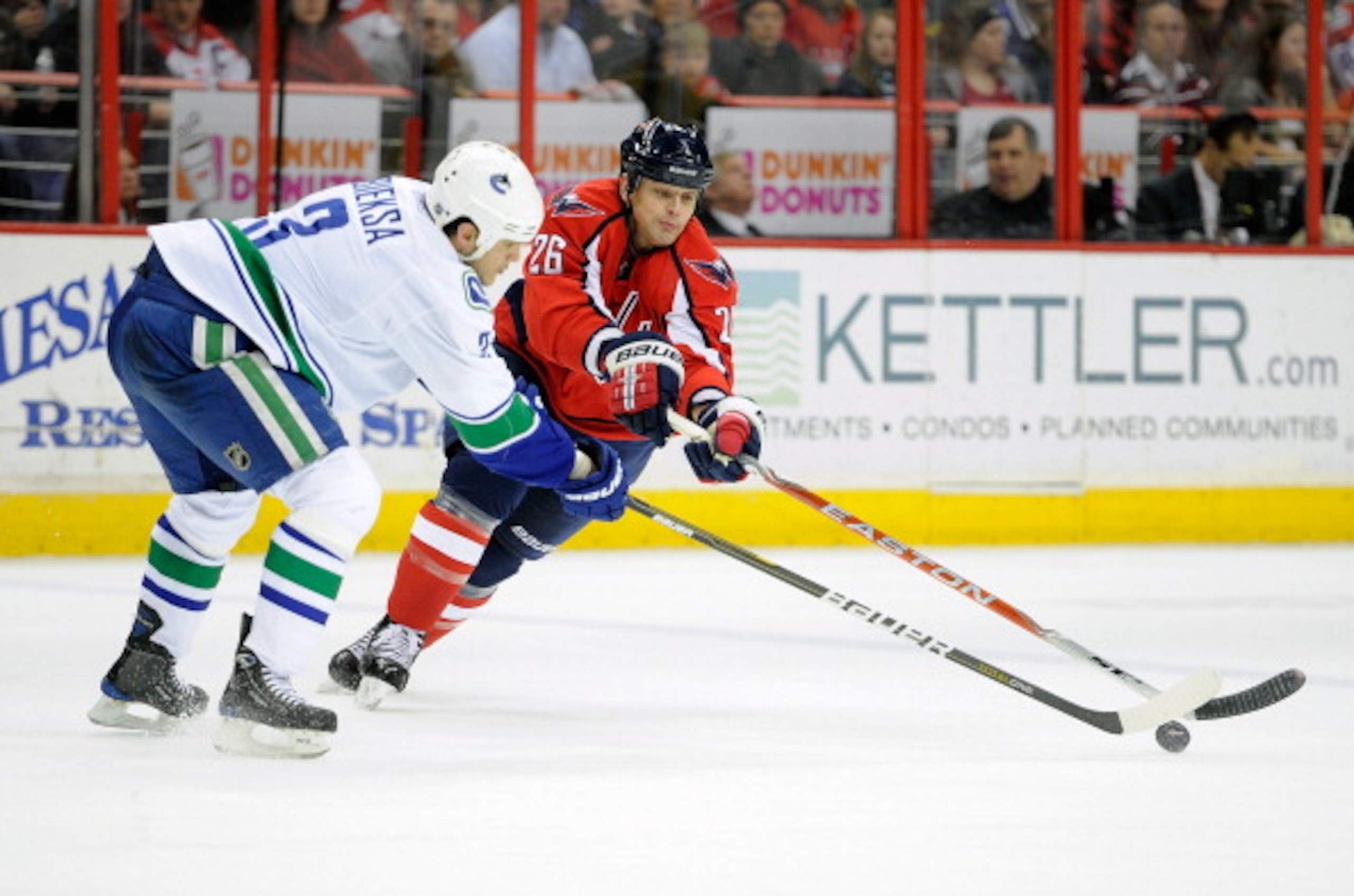 WASHINGTON - JANUARY 14:  Kevin Bieksa #3 of the Vancouver Canucks battles for the puck with Matt Hendricks #26 of the Washington Capitals at the Verizon Center on January 14, 2011 in Washington, DC.  (Photo by Greg Fiume/Getty Images)
