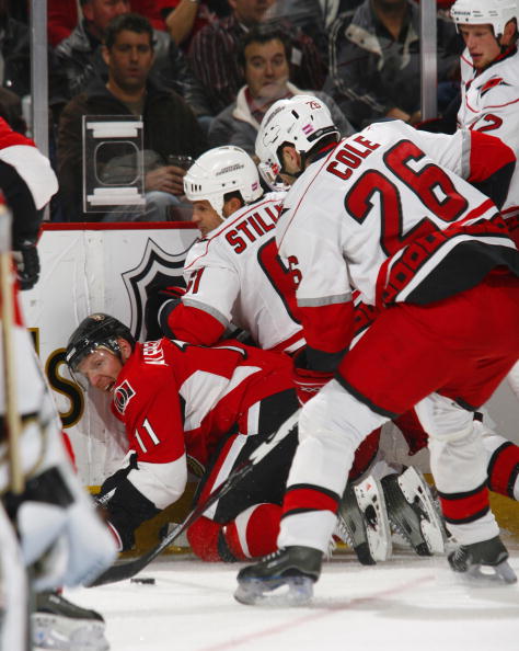 OTTAWA, CANADA- OCTOBER 11:  Daniel Alfredsson #11 of the Ottawa Senators is knocked to the ice by the combined efforts of Cory Stillman #61;Erik Cole #26 and Eric Staal #12 of the Carolina Hurricanes during first period action of a game on October 11, 20