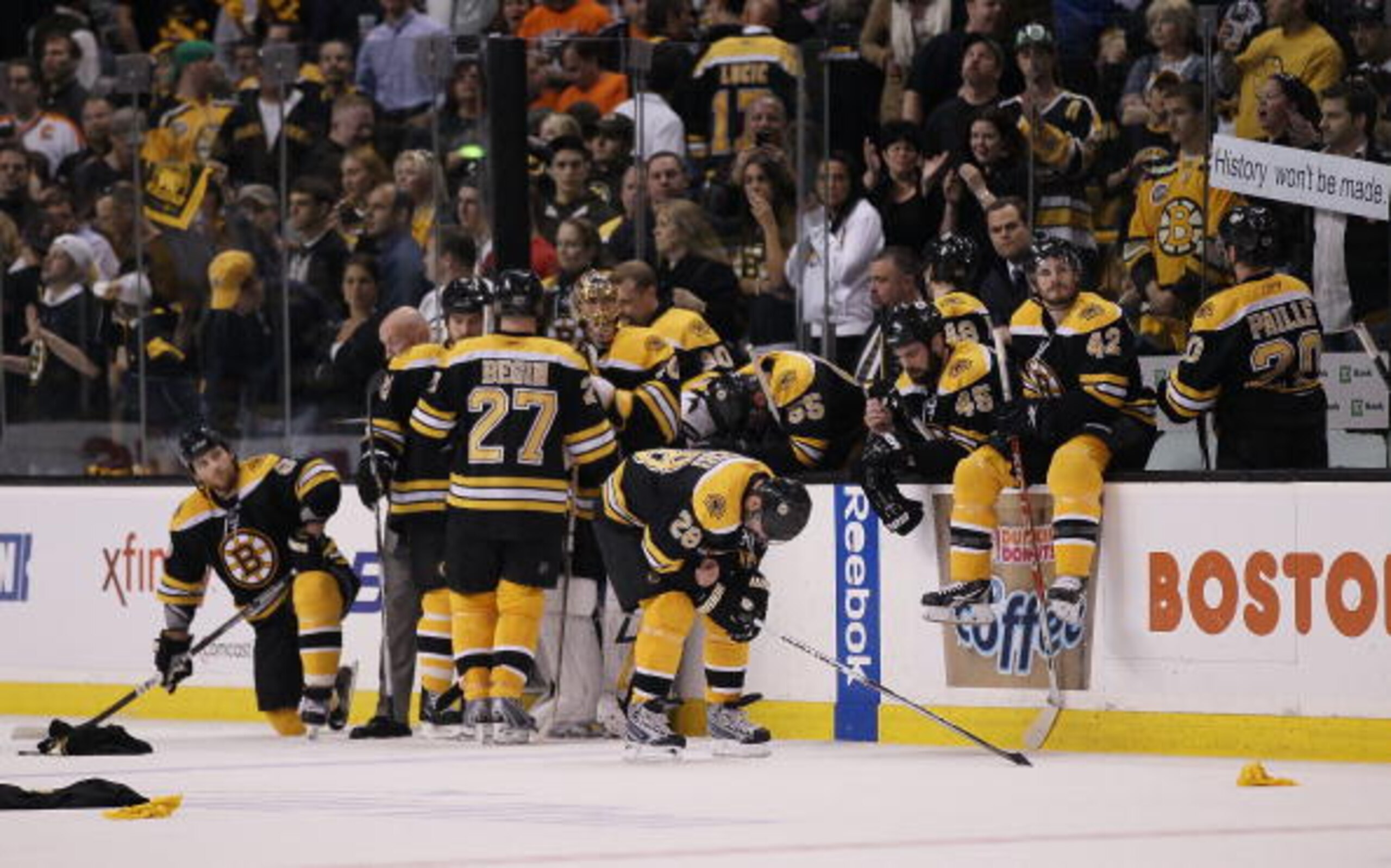 BOSTON - MAY 14:  The  Boston Bruins sit near their bench as the Philadelphia Flyers celebrate the win in Game Seven of the Eastern Conference Semifinals during the 2010 NHL Stanley Cup Playoffs at TD Garden on May 14, 2010 in Boston, Massachusetts. The F