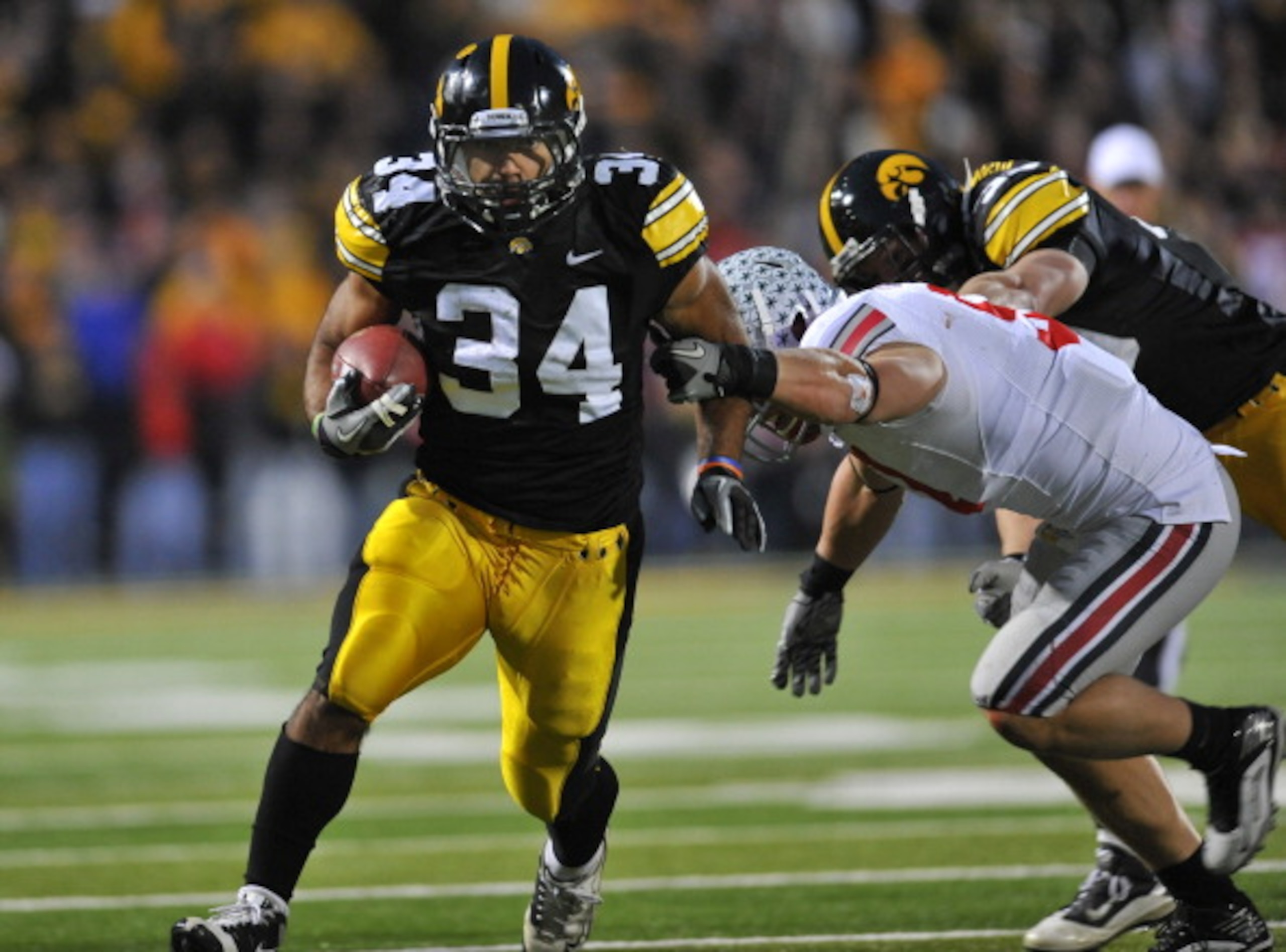 IOWA CITY, IA - NOVEMBER 20:  Running back Marcus Coker #34 of the University of Iowa Hawkeyes drives the ball past linebacker Ross Homan #51 of the Ohio State Buckeyes during the second half of play at Kinnick Stadium on November 20, 2010 in Iowa City, I