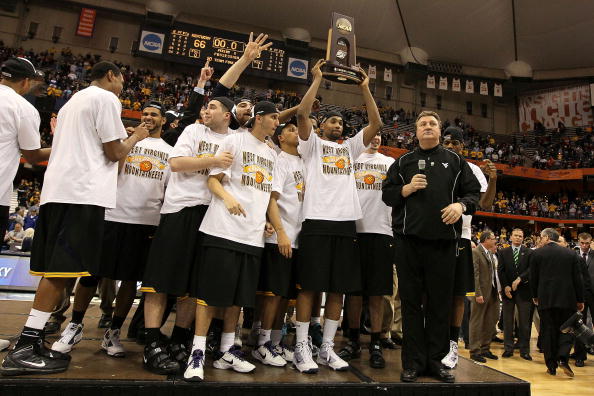 SYRACUSE, NY - MARCH 27:  Head coach Bob Huggins (R) of the West Virginia Mountaineers gets set to address the crowd as his playes celebrate with the East Regional trophy (held by Da'Sean Butler #1) after West Virginia won 73-66 against the Kentucky Wildc