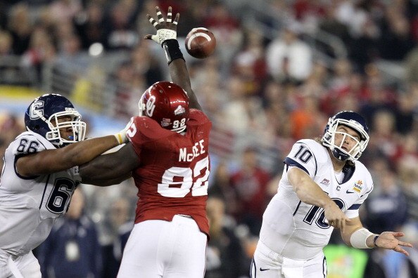 GLENDALE, AZ - JANUARY 01:  Zach Frazer #10 of the Connecticut Huskies throws the ball around the arm of Stacy McGee #92 of the Oklahoma Sooners in the third quarter during the Tostitos Fiesta Bowl at the Universtity of Phoenix Stadium on January 1, 2011