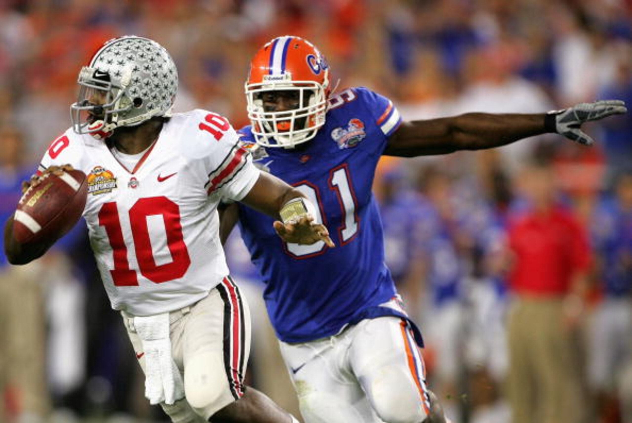 GLENDALE, AZ - JANUARY 08:  Quarterback Troy Smith #10 of the Ohio State Buckeyes scrambles with the ball under pressure from Derrick Harvey #91 of the Florida Gators during the 2007 Tostitos BCS National Championship Game at the University of Phoenix Sta