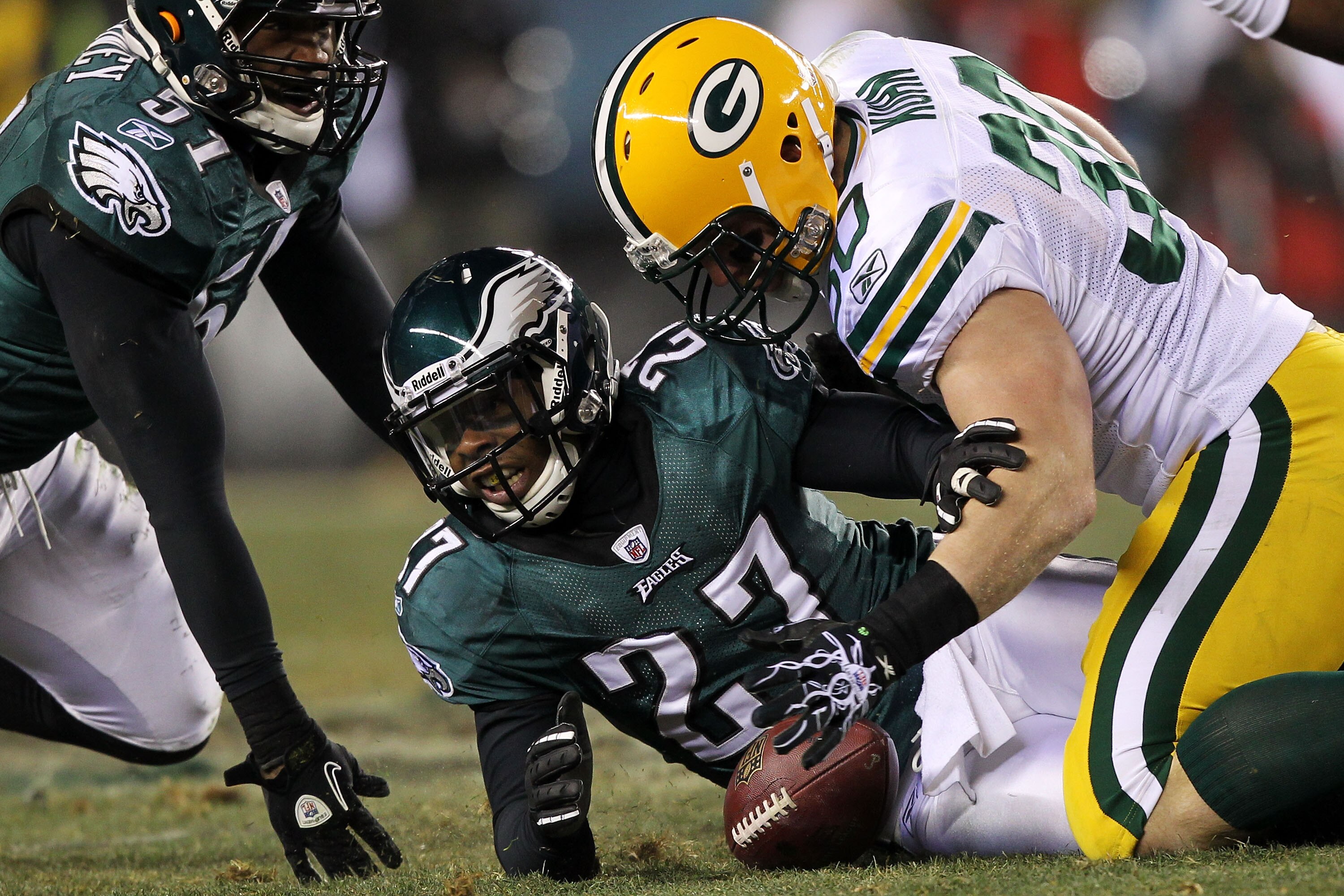 PHILADELPHIA, PA - JANUARY 09:  John Kuhn #30 of the Green Bay Packers fights for a fumble against Quintin Mikell #27 and Jamar Chaney #51 of the Philadelphia Eagles during the 2011 NFC wild card playoff game at Lincoln Financial Field on January 9, 2011