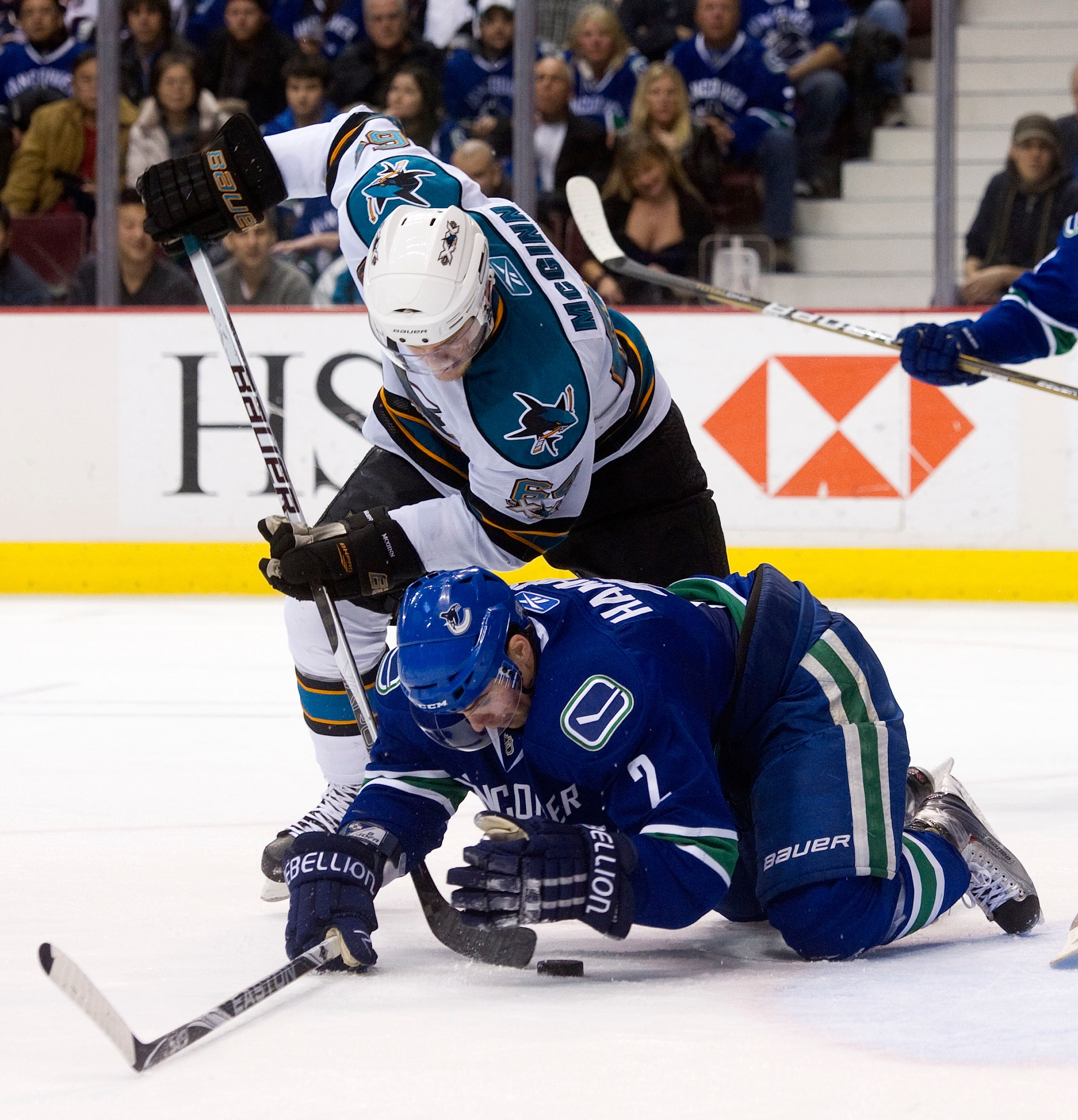 VANCOUVER, CANADA - JANUARY 20: Dan Hamhuis #2 of the Vancouver Canucks tries to cover up the puck during a scramble while Jamie McGinn #64 of the San Jose Sharks tries to dig it loose during the third period in NHL action on January 20, 2011 at Rogers Ar