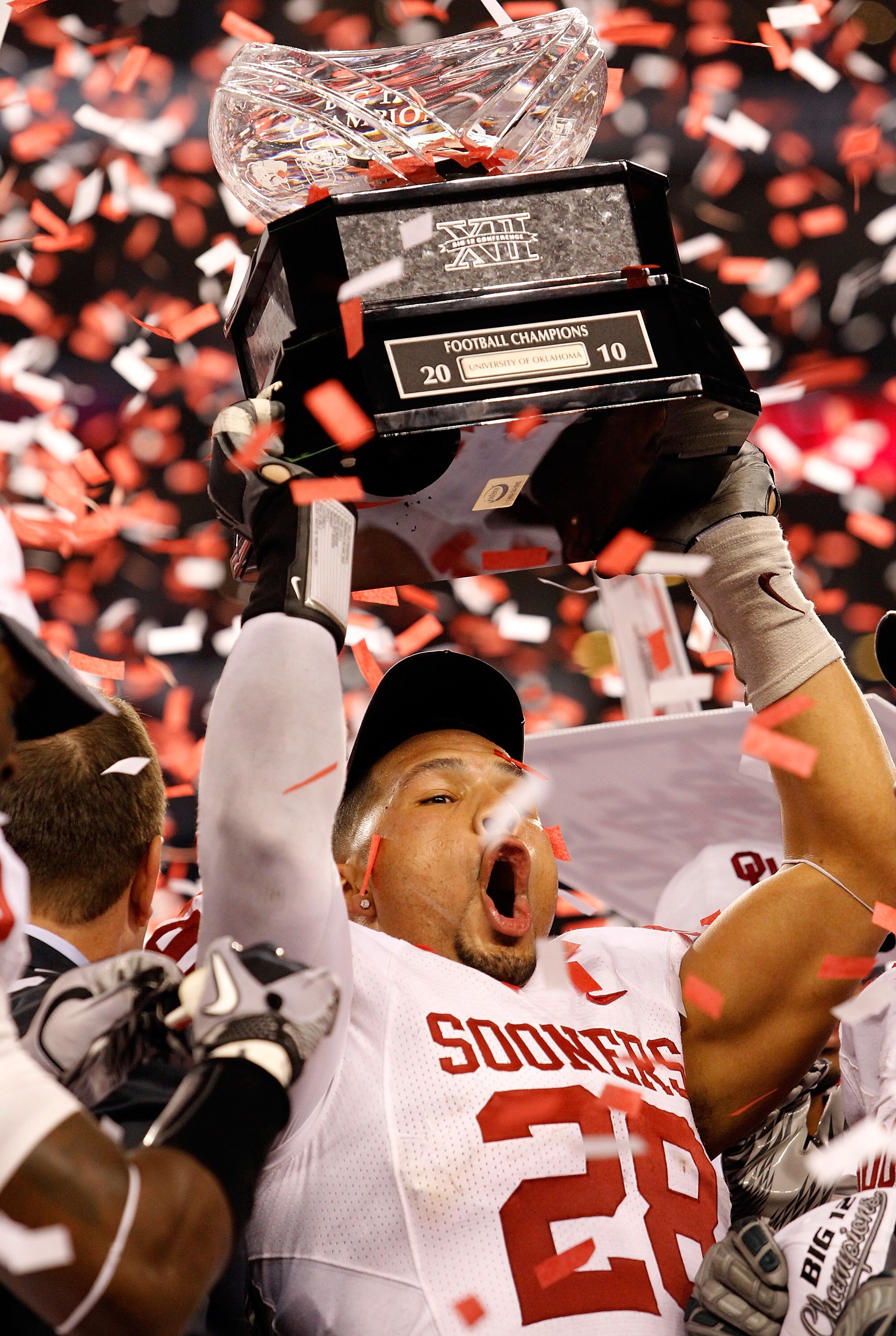 ARLINGTON, TX - DECEMBER 04:  Linebacker Travis Lewis #28 of the Oklahoma Sooners celebrates with the Big 12 Championship Trophy after the Sooners beat the Nebraska Cornhuskers 23-20 at Cowboys Stadium on December 4, 2010 in Arlington, Texas.  (Photo by T