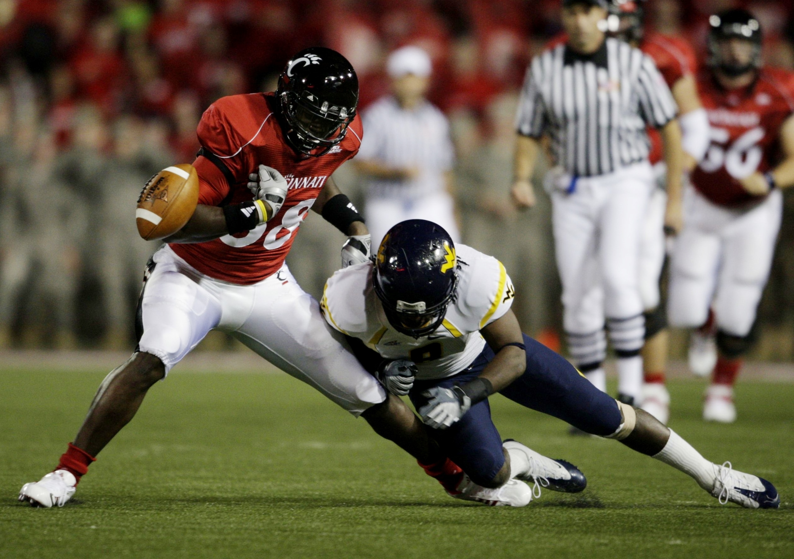 CINCINNATI - NOVEMBER 13:  Adrien Robinson #88 of the Cincinnati Bearcats is hit by Keith Tandy #8 of the West Virginia Mountaineers to fumble the ball in the first quarter of the game at Nippert Stadium on November 13, 2009 in Cincinnati, Ohio.  (Photo b