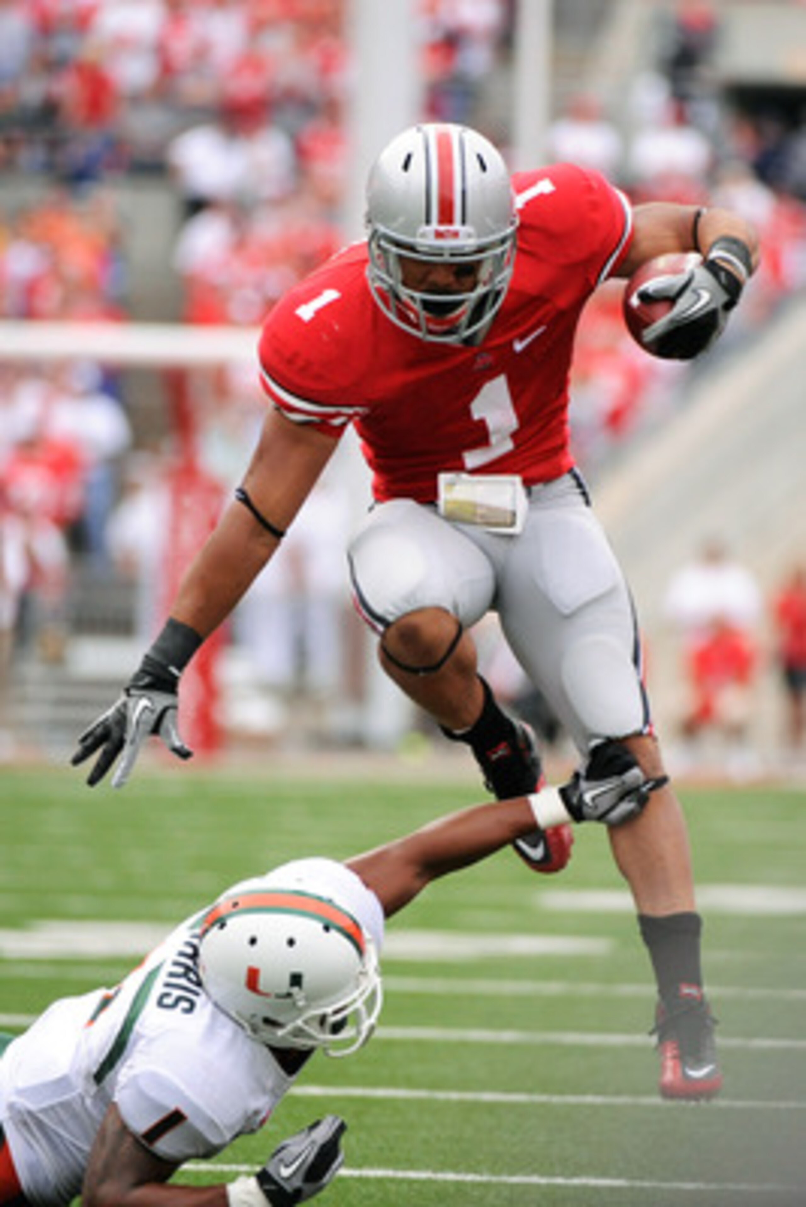 COLUMBUS, OH - SEPTEMBER 11:  Dan Herron #1 of the Ohio State Buckeyes leaps over the tackle attempt of Brandon Harris #1 of the Miami Hurricanes at Ohio Stadium on September 11, 2010 in Columbus, Ohio.  (Photo by Jamie Sabau/Getty Images)