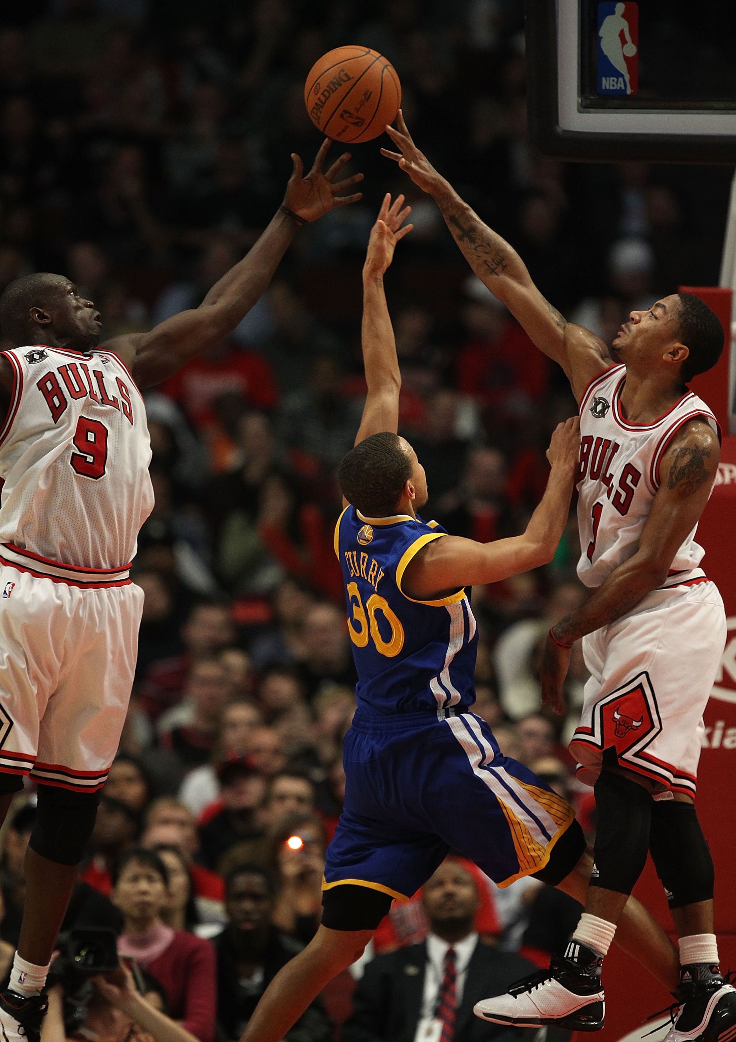 CHICAGO - NOVEMBER 11: Loul Deng #9 and Derrick Rose #1 of the Chicago Bulls block a shot by Stephen Curry #30 of the Golden State Warriors at the United Center on November 11, 2010 in Chicago, Illinois. The Bulls defeated the Warriors 120-90. NOTE TO USE CHICAGO - NOVEMBER 11: Loul Deng #9 and Derrick Rose #1 of the Chicago Bulls block a shot by Stephen Curry #30 of the Golden State Warriors at the United Center on November 11, 2010 in Chicago, Illinois. The Bulls defeated the Warriors 120-90. NOTE TO USE