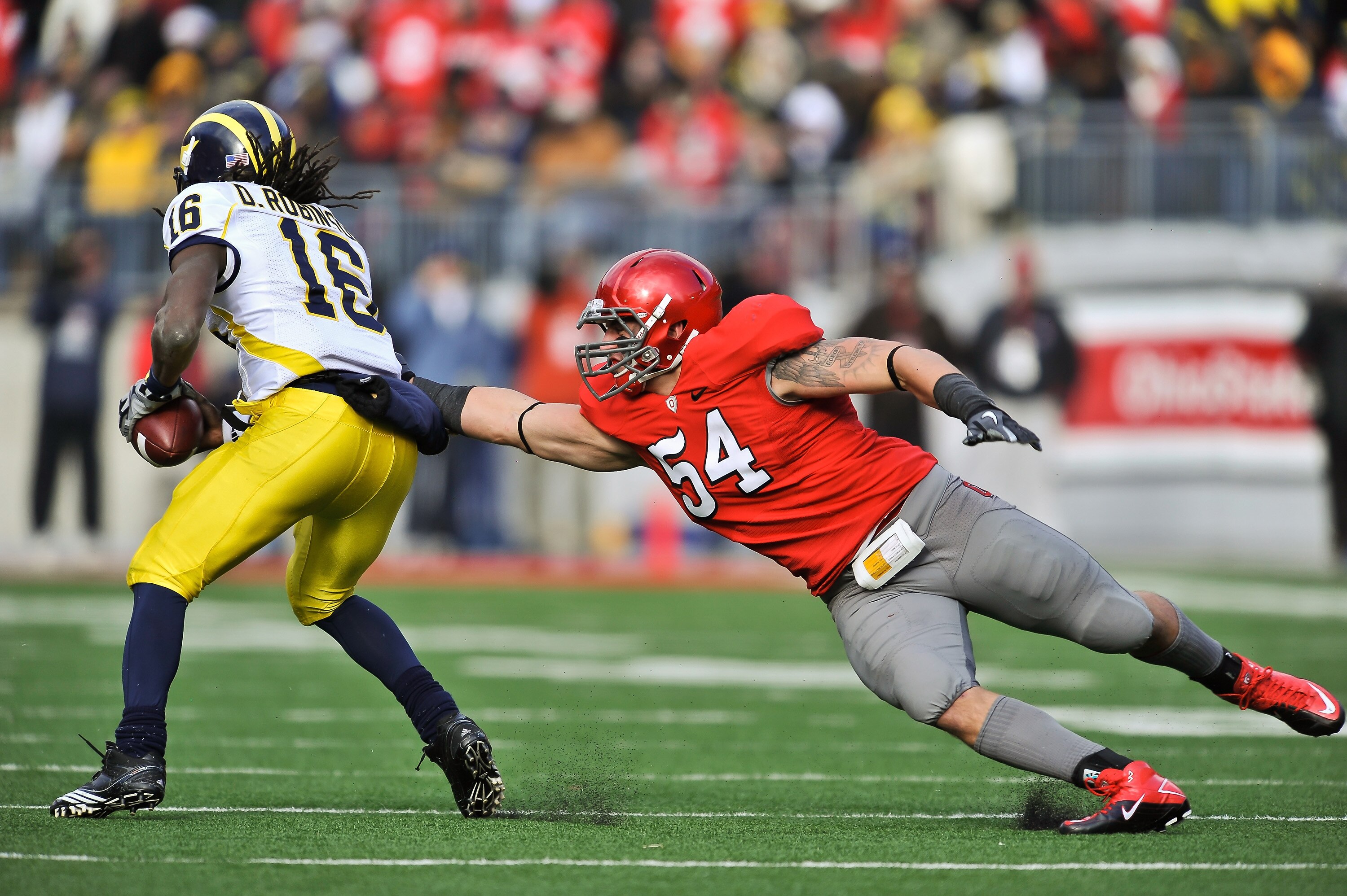 COLUMBUS, OH - NOVEMBER 27:  John Simon #54 of the Ohio State Buckeyes attempts to tackle quarterback Denard Robinson #16 of the Michigan Wolverines at Ohio Stadium on November 27, 2010 in Columbus, Ohio.  (Photo by Jamie Sabau/Getty Images)