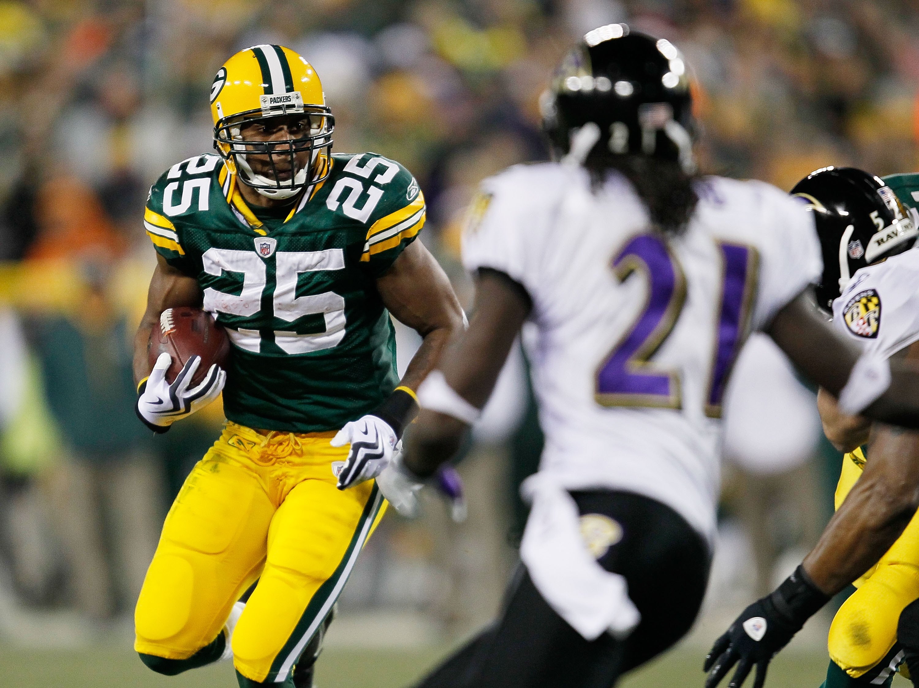 GREEN BAY, WI - DECEMBER 07: Ryan Grant #25 of the Green Bay Packers runs as Lardarius Webb #21 of the Baltimore Ravens closes in at Lambeau Field on December 7, 2009 in Green Bay, Wisconsin. The Packers defeated the Ravens 27-17. (Photo by Jonathan Danie