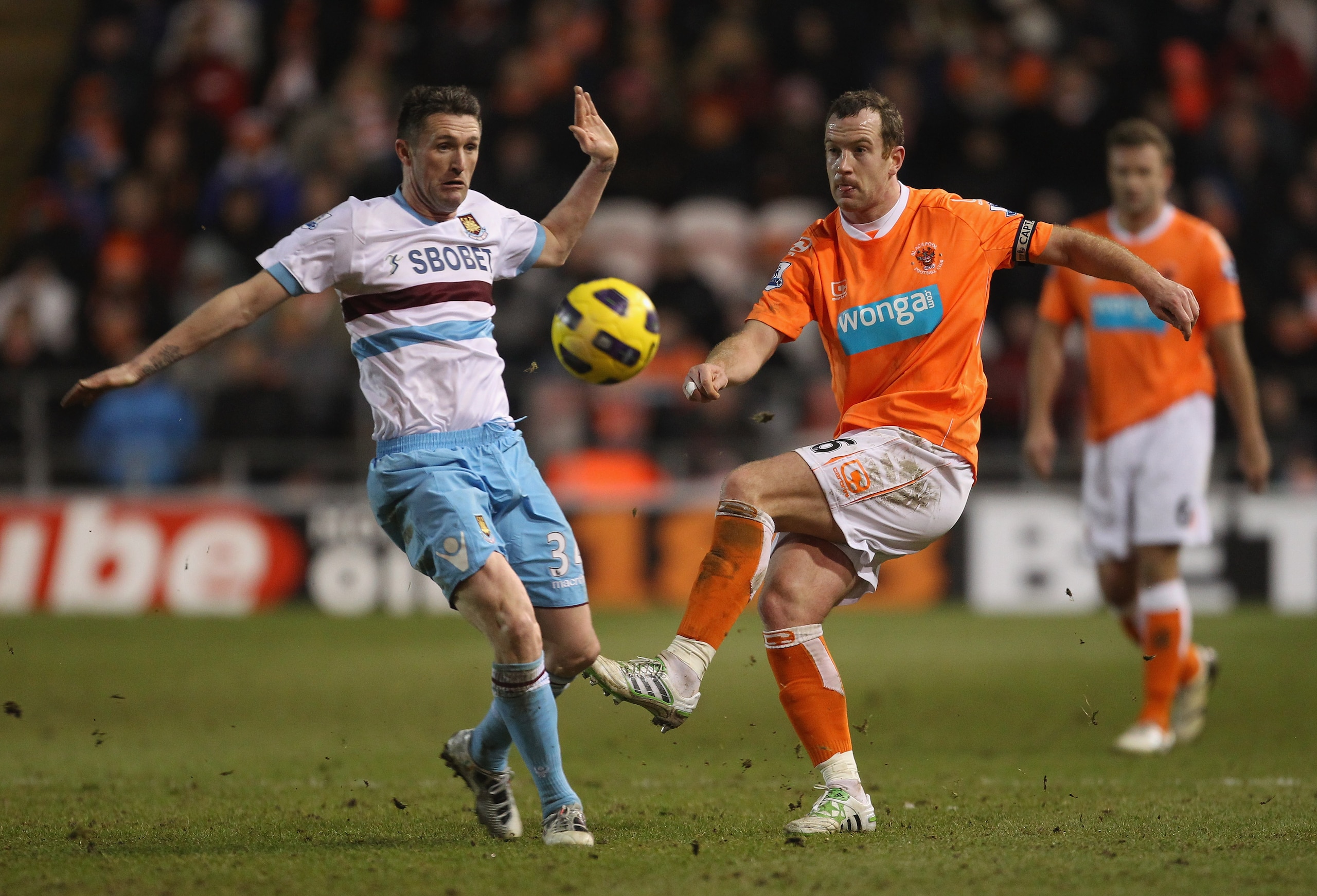 BLACKPOOL, ENGLAND - FEBRUARY 02:  Charlie Adam of Blackpool shoots past Robbie Keane of West Ham United during the Barclays Premier League match between Blackpool and West Ham United at Bloomfield Road on February 2, 2011 in Blackpool, England.  (Photo b