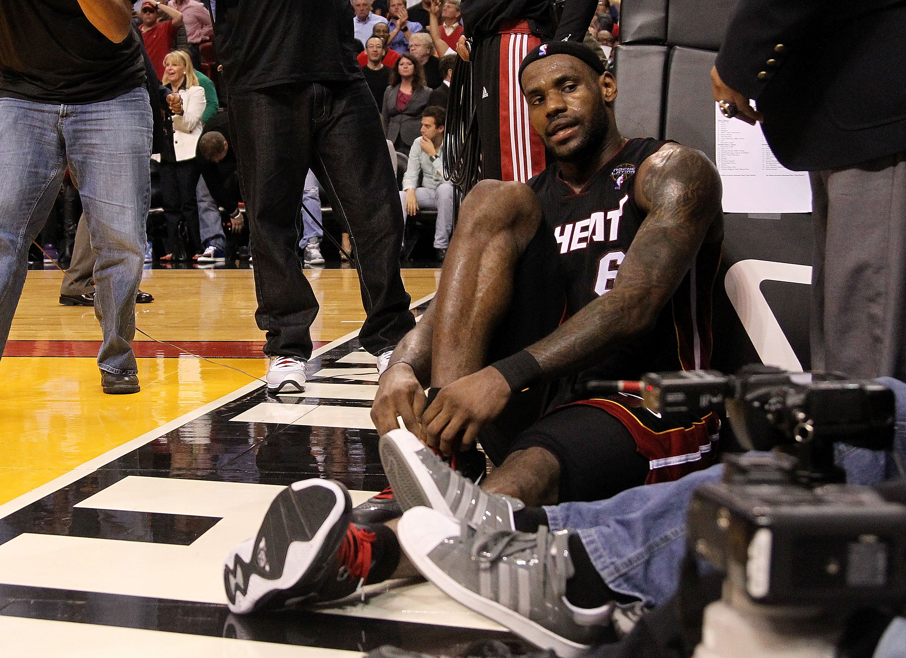 MIAMI, FL - MARCH 10:  LeBron James #6 of the Miami Heat ties his shoe after falling on a camerman during a game against  the Los Angeles Lakers at American Airlines Arena on March 10, 2011 in Miami, Florida. NOTE TO USER: User expressly acknowledges and 