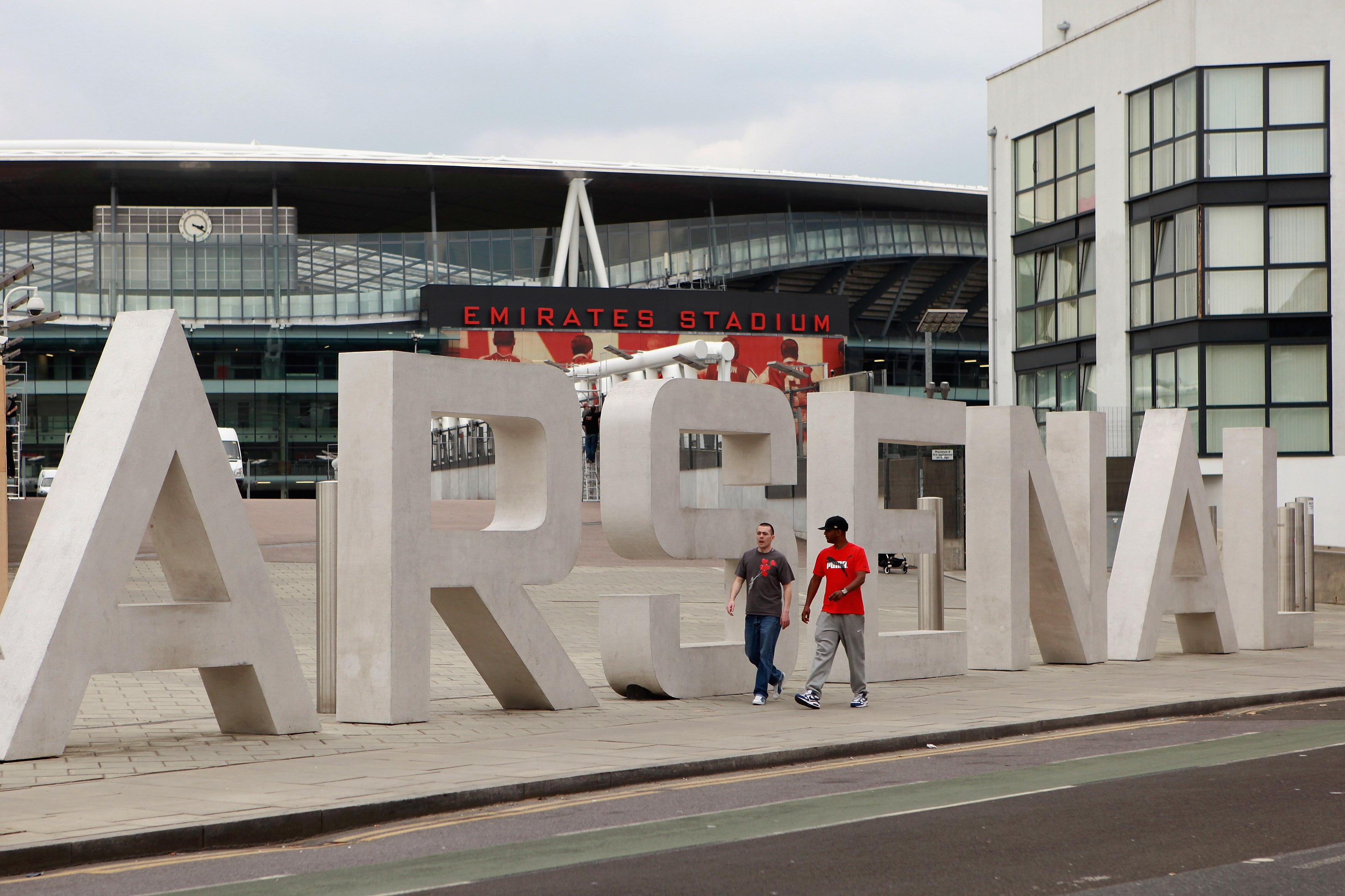 LONDON, ENGLAND - APRIL 11:  Two men walk past the sign for Arsenal Football Club's Emirates Stadium on April 11, 2011 in London, England. American businessman Stan Kroenke's company 'Kroenke Sports Enterprises' has increased its shareholding in Arsenal t