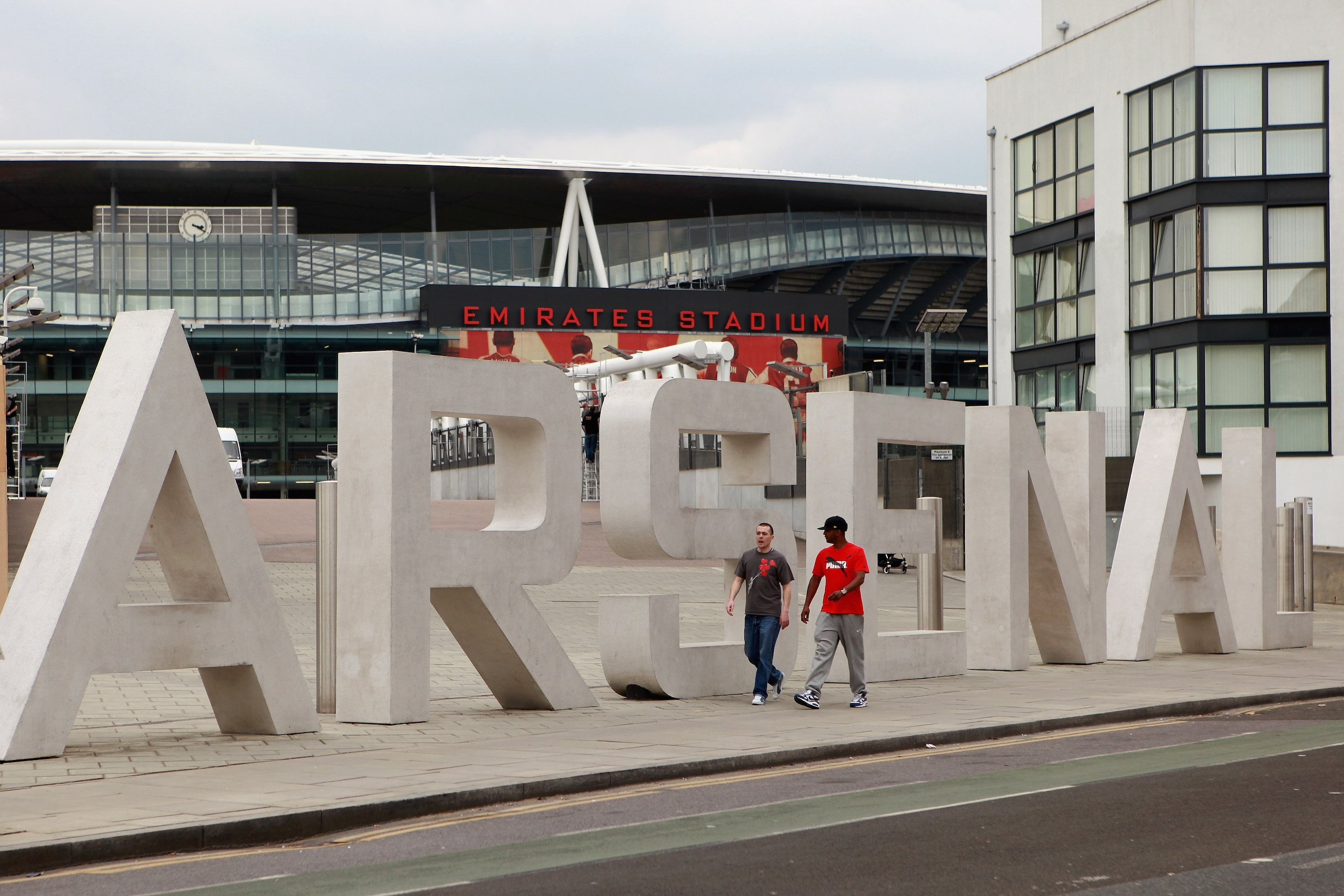 LONDON, ENGLAND - APRIL 11:  Two men walk past the sign for Arsenal Football Club's Emirates Stadium on April 11, 2011 in London, England. American businessman Stan Kroenke's company 'Kroenke Sports Enterprises' has increased its shareholding in Arsenal t