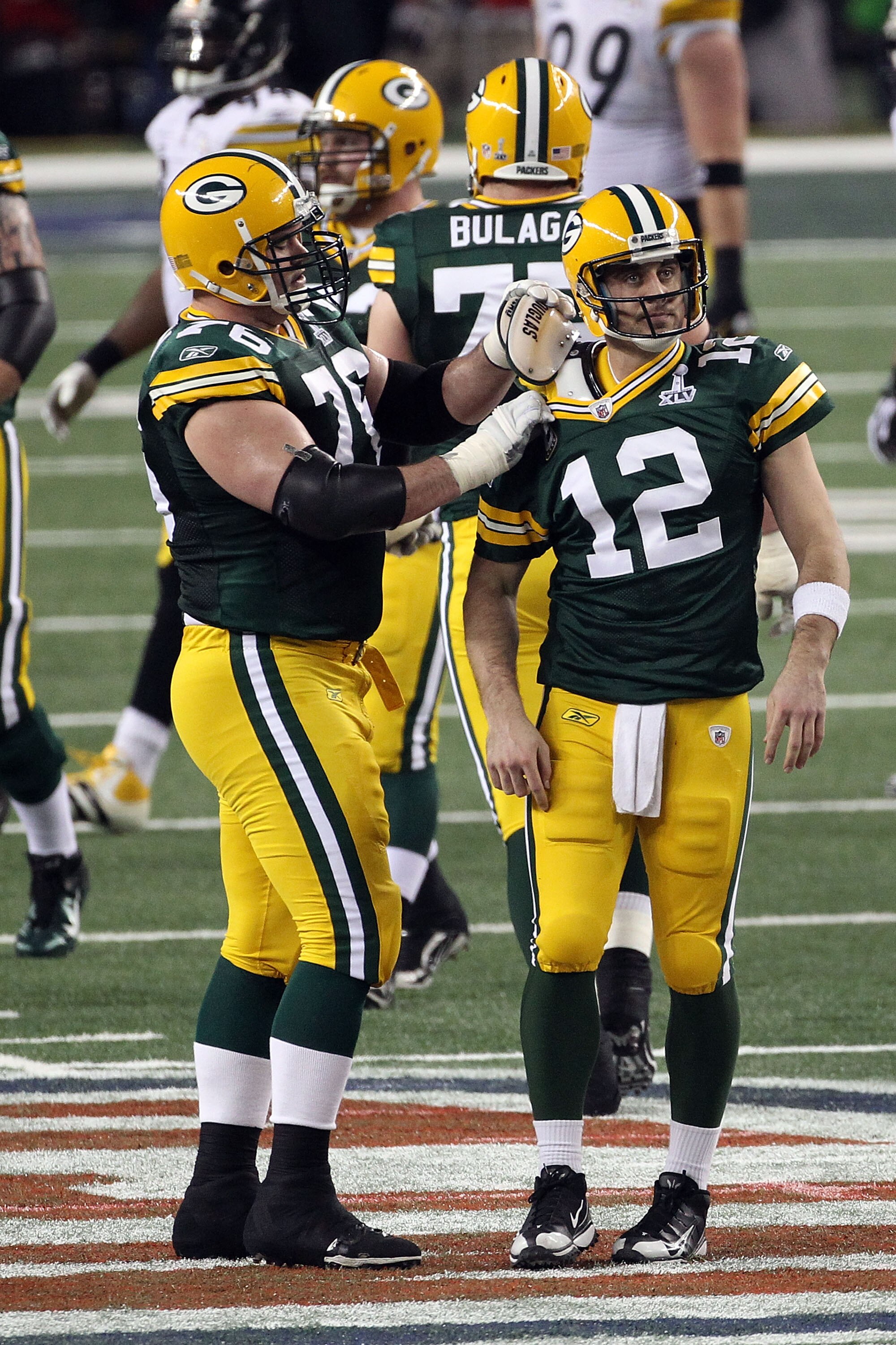 ARLINGTON, TX - FEBRUARY 06: Chad Clifton #76 of the Green Bay Packers fixes teammate Aaron Rodgers #12 shoulder pad during Super Bowl XLV against the Pittsburgh Steelers at Cowboys Stadium on February 6, 2011 in Arlington, Texas.  (Photo by Streeter Leck