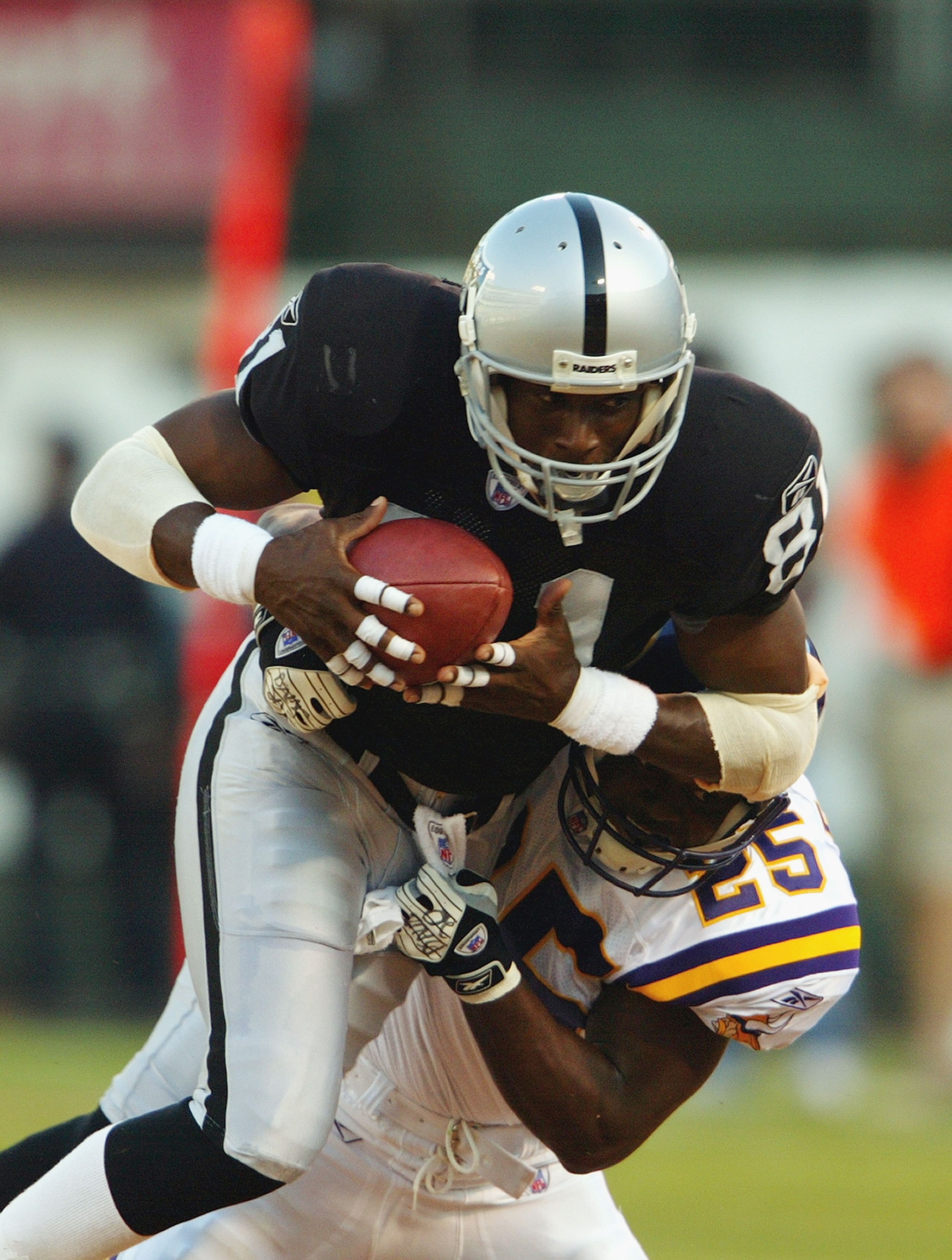 OAKLAND, CA - AUGUST 22 :  Tim Brown #81 of the Oakland Raiders is brought down by Eric Kelly #25 of the Minnesota Vikings on August 22, 2003 at the Network Associates Coliseum in Oakland, California.  The Vikings defeated the Raiders 21-6.  (Photo by Jus