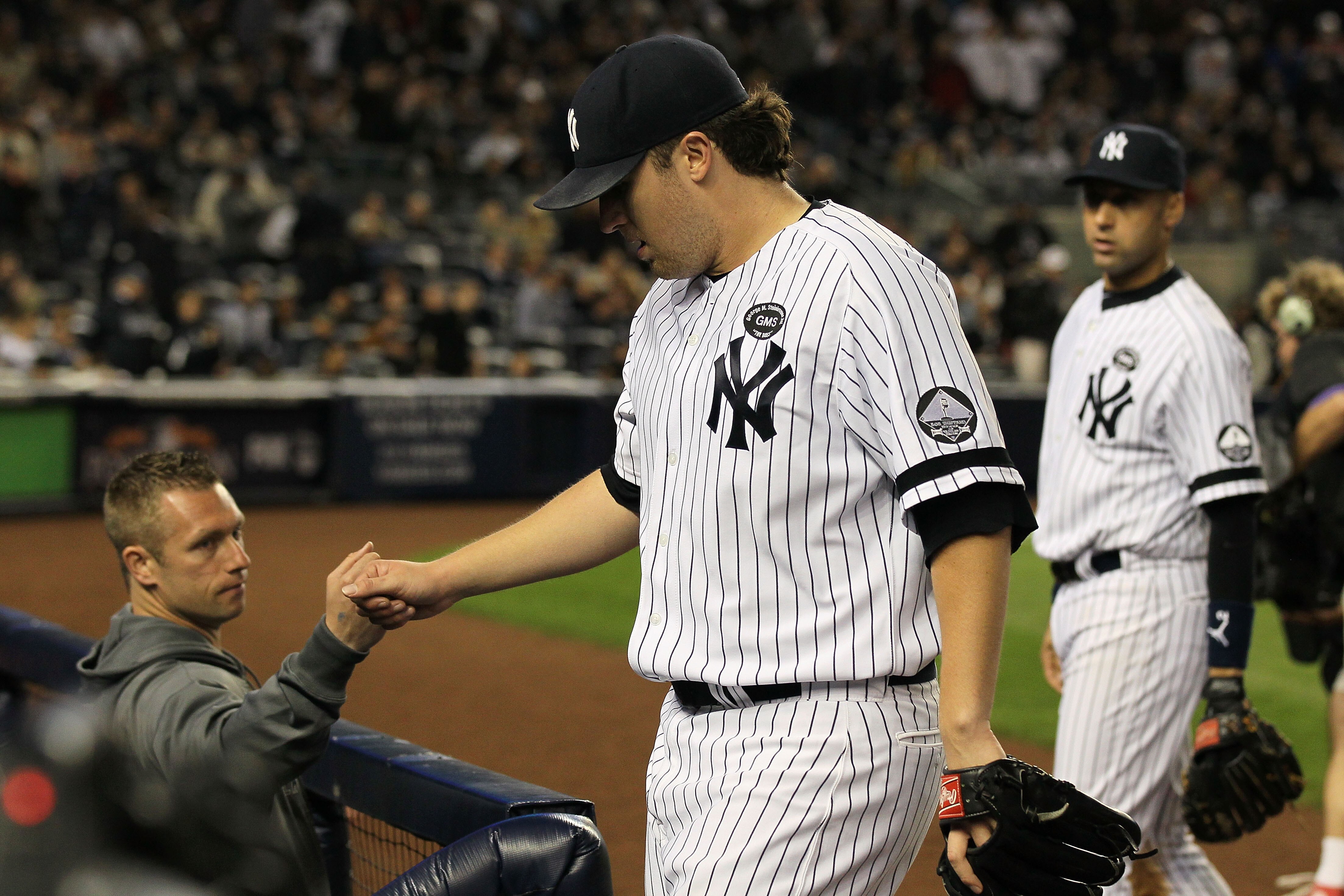 NEW YORK - OCTOBER 09:  Phil Hughes #65 of the New York Yankees is congratulated by teammates as he returns to the dugout at the end of an inning against the Minnesota Twins during Game Three of the ALDS part of the 2010 MLB Playoffs at Yankee Stadium on