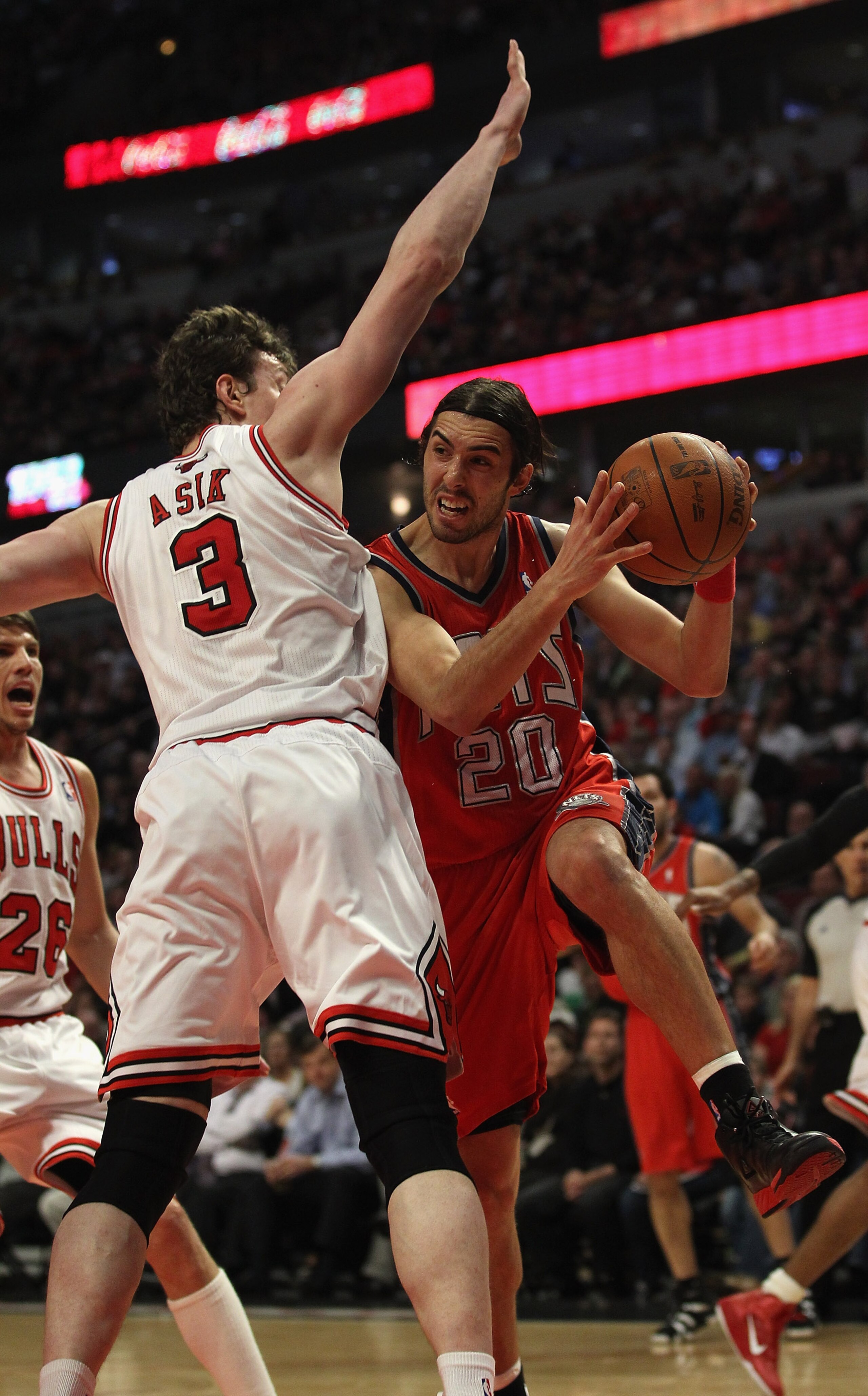 CHICAGO, IL - APRIL 13: Sasha Vujacic #20 of the New Jersey Nets passes the ball around Omer Asik #3 of the Chicago Bulls at the United Center on April 13, 2011 in Chicago, Illinois. The Bulls defeated the Nets 97-92. NOTE TO USER: User expressly acknowle