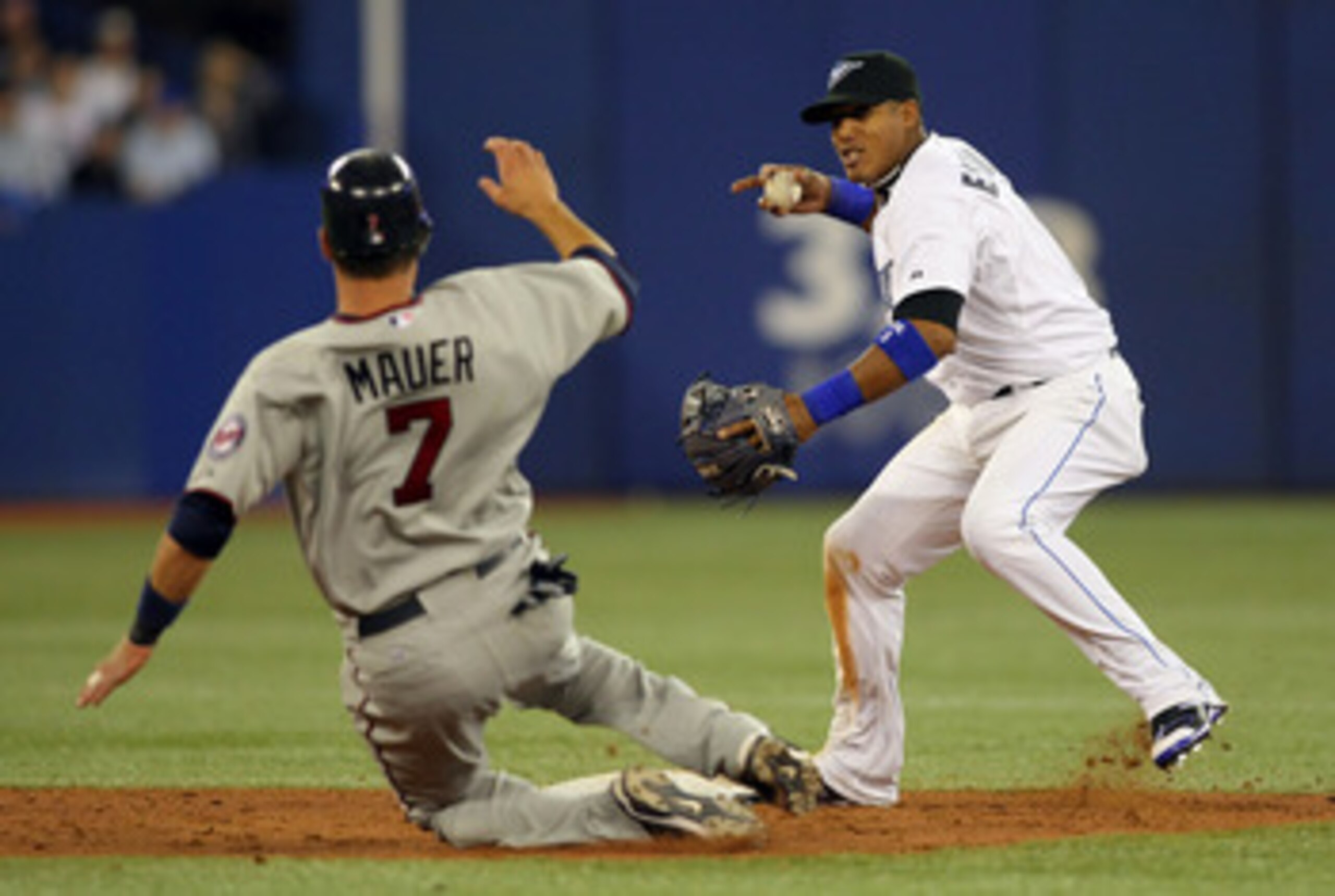TORONTO,CANADA - APRIL 1:  Yunel Escobar #5 of the Toronto Blue Jays turns a double play as Joe Mauer #7 of the Minnesota Twins slides into 2nd base on opening day during their MLB game at the Rogers Centre April 1, 2011 in Toronto, Ontario, Canada.(Photo