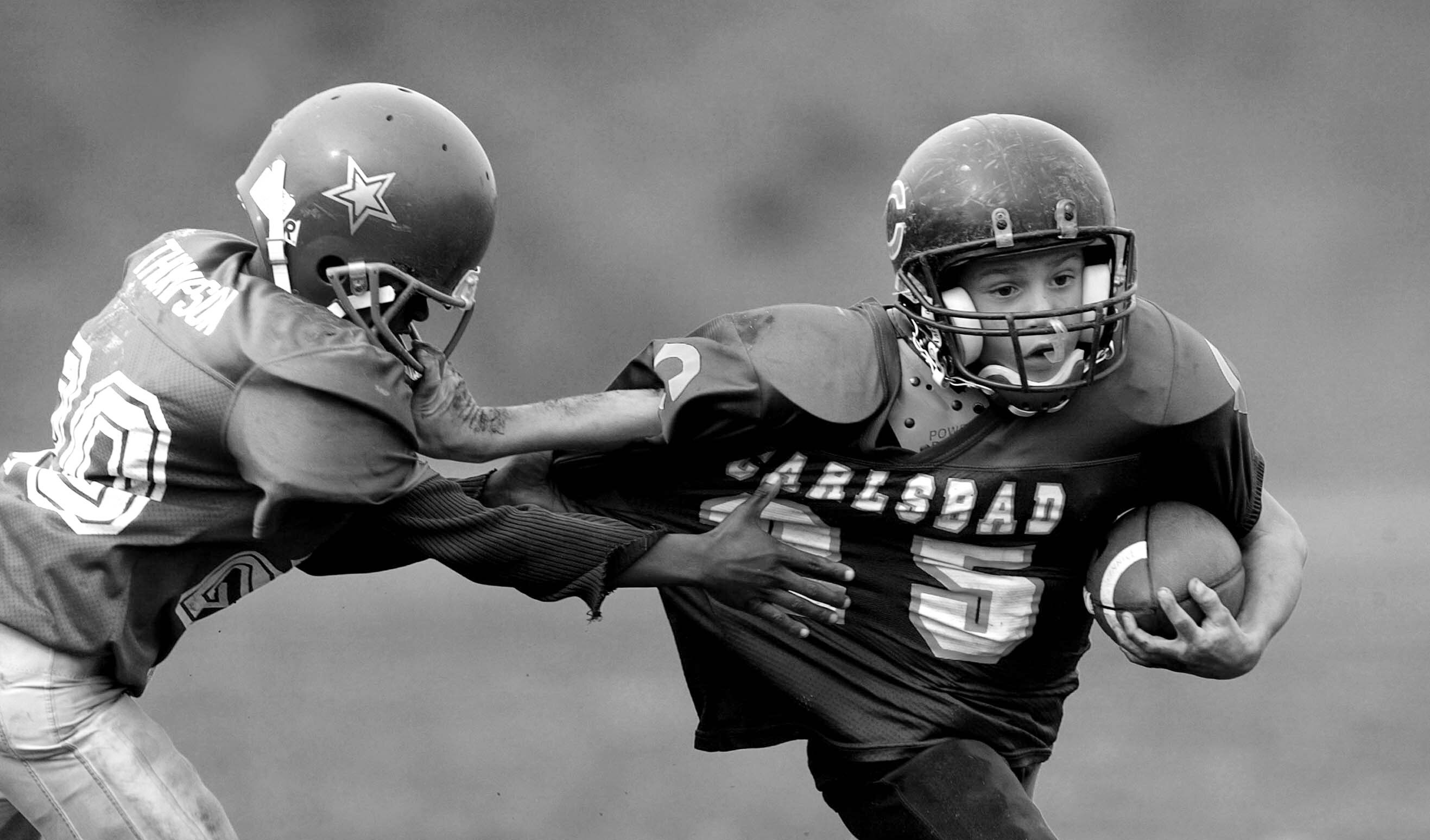 SAN DIEGO - November 9:   Runningback Armani Aburto #35 of the Carlsbad Mighty Lancers (8 & under) runs with the ball as he facemasks #20 Jarryn Thompson of the Torrey Pines Falcons during the Pop Warner Division Finals on November 9, 2002 at Carlsbad Hig