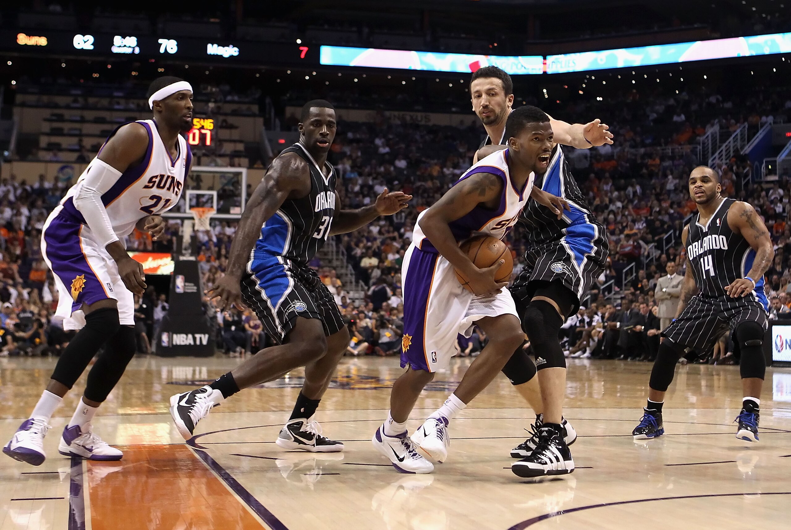PHOENIX, AZ - MARCH 13:  Aaron Brooks #0 of the Phoenix Suns drives the ball past Brandon Bass #30 and Hedo Turkoglu #15  of the Orlando Magic during the NBA game at US Airways Center on March 13, 2011 in Phoenix, Arizona. The Magic defeated the Suns 111-