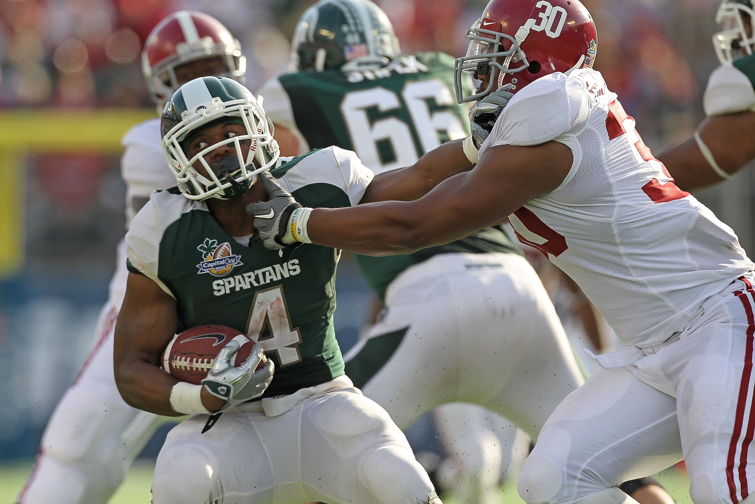 ORLANDO, FL - JANUARY 01: Edwin Baker #4 of the Michigan State Spartans stiff arms Dont'a Hightower #30 of the Alabama Crimson Tide during the Capitol One Bowl at the Florida Citrus Bowl on January 1, 2011 in Orlando, Florida. (Photo by Mike Ehrmann/Get ORLANDO, FL - JANUARY 01: Edwin Baker #4 of the Michigan State Spartans stiff arms Dont'a Hightower #30 of the Alabama Crimson Tide during the Capitol One Bowl at the Florida Citrus Bowl on January 1, 2011 in Orlando, Florida. (Photo by Mike Ehrmann/Get