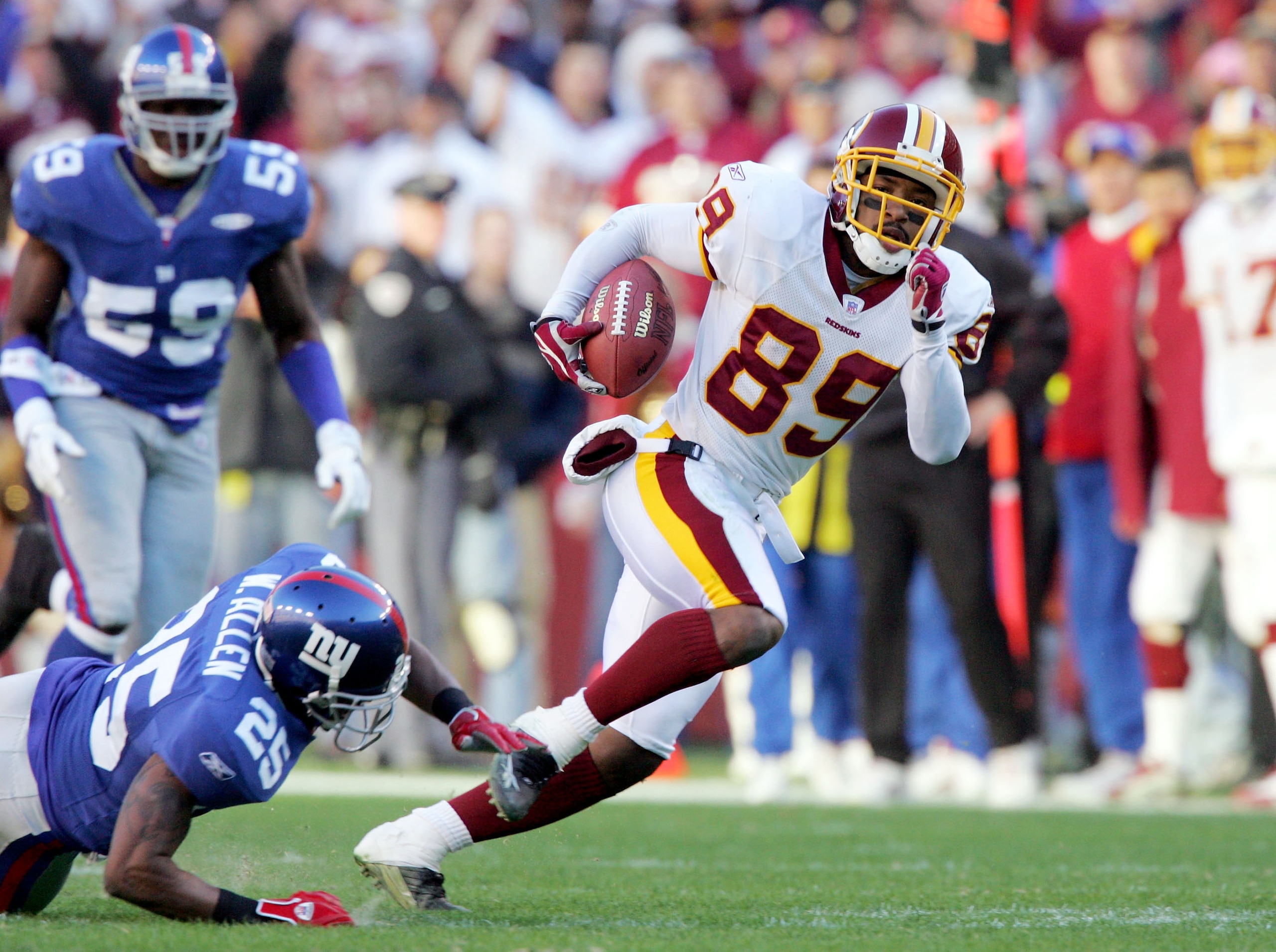 LANDOVER, MD - DECEMBER 24:  Santana Moss #89 of the Washington Redskins breaks a tackle from Will Allen #25 of the New York Giants and heads for the endzone to score his third touchdown of the day on December 24, 2005 at FedEx Field in Landover, Maryland