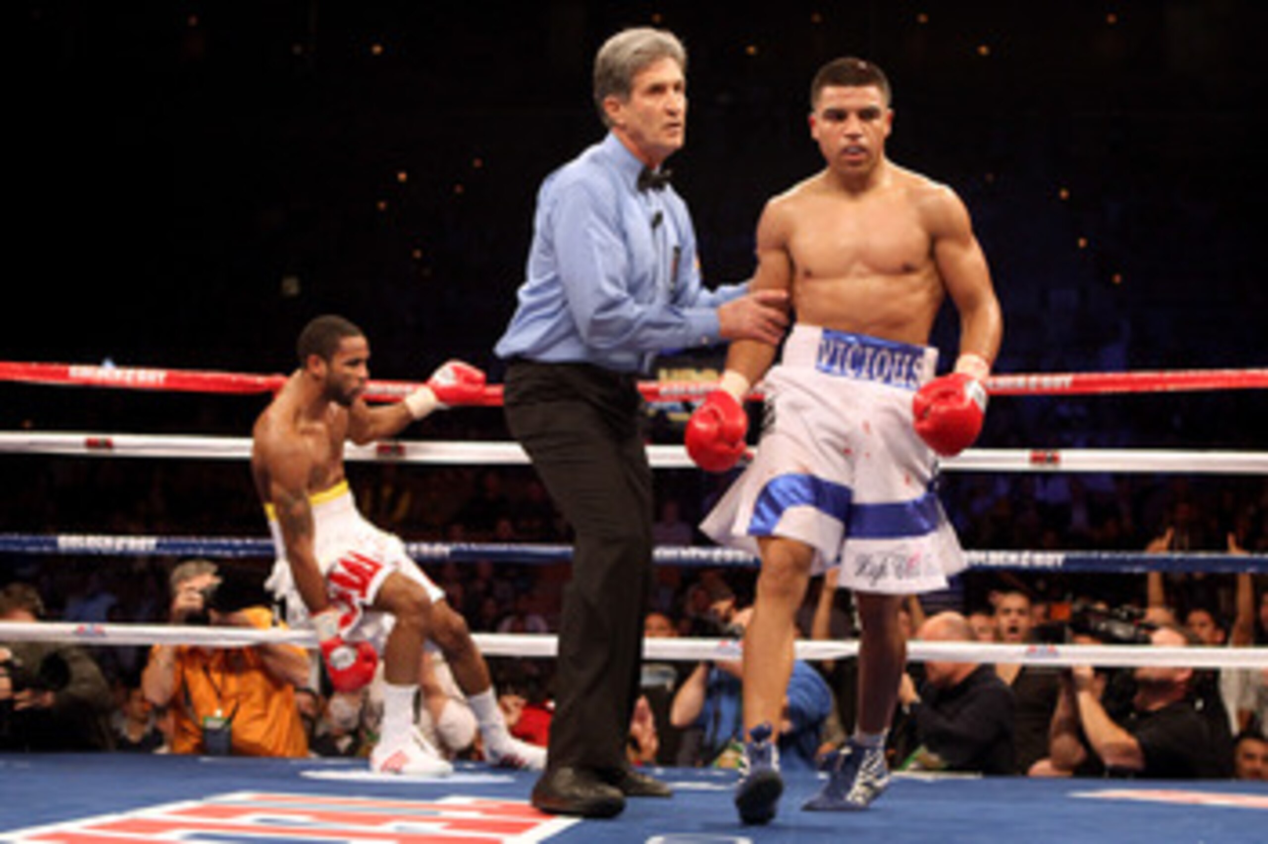 LAS VEGAS - DECEMBER 11:  (R-L) Victor Ortiz walks back to his corner with referee Vic Drakulich after Ortiz knocks down Lamont Petersen in the third round during the super lightweight fight at Mandalay Bay Events Center on December 11, 2010 in Las Vegas,