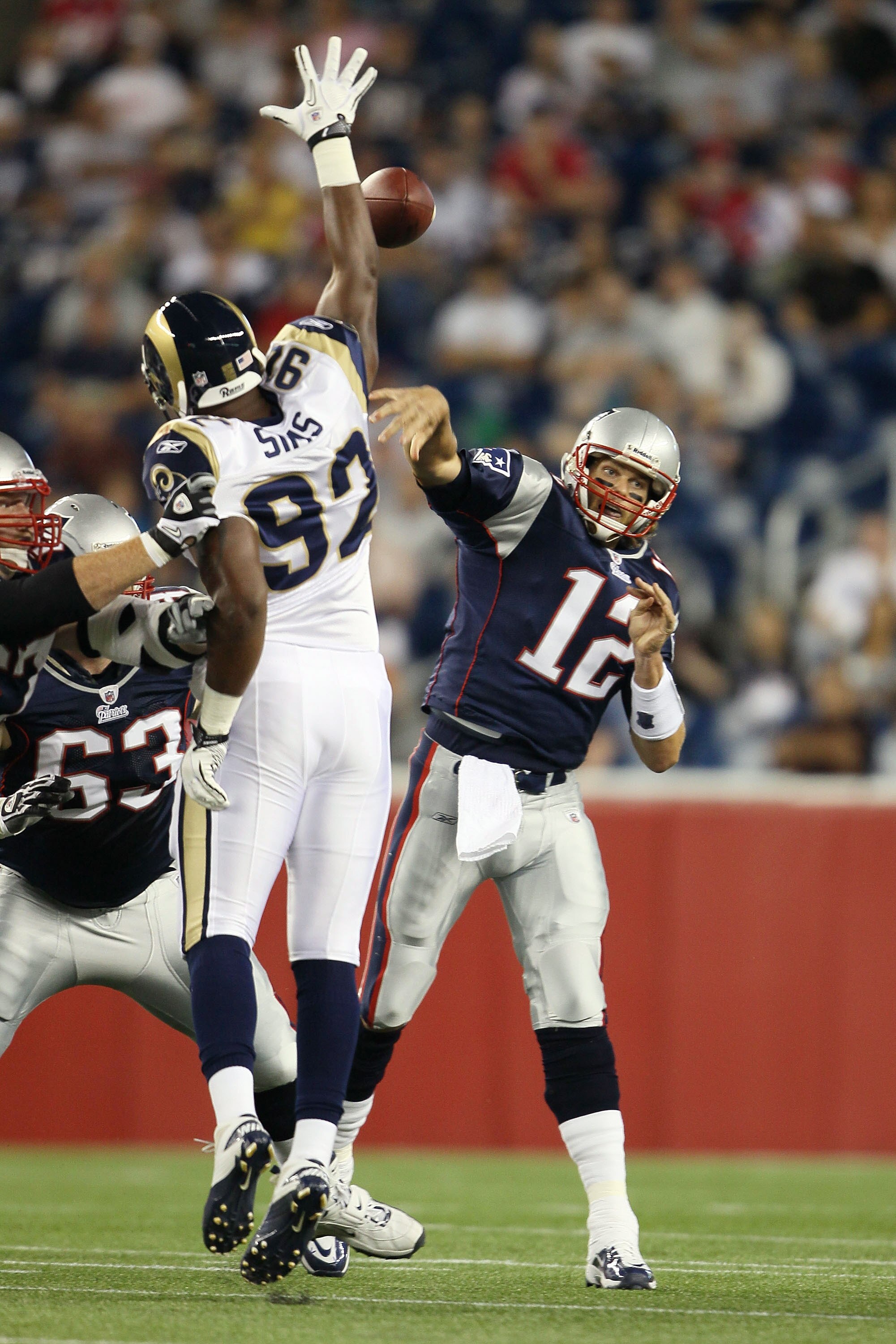 FOXBORO, MA - AUGUST 26:  Tom Brady #12 of the New England Patriots passes the ball under pressure from Eugene Sims #92 of the St. Louis Rams on August 26, 2010 at Gillette Stadium in Foxboro, Massachusetts.  (Photo by Elsa/Getty Images)