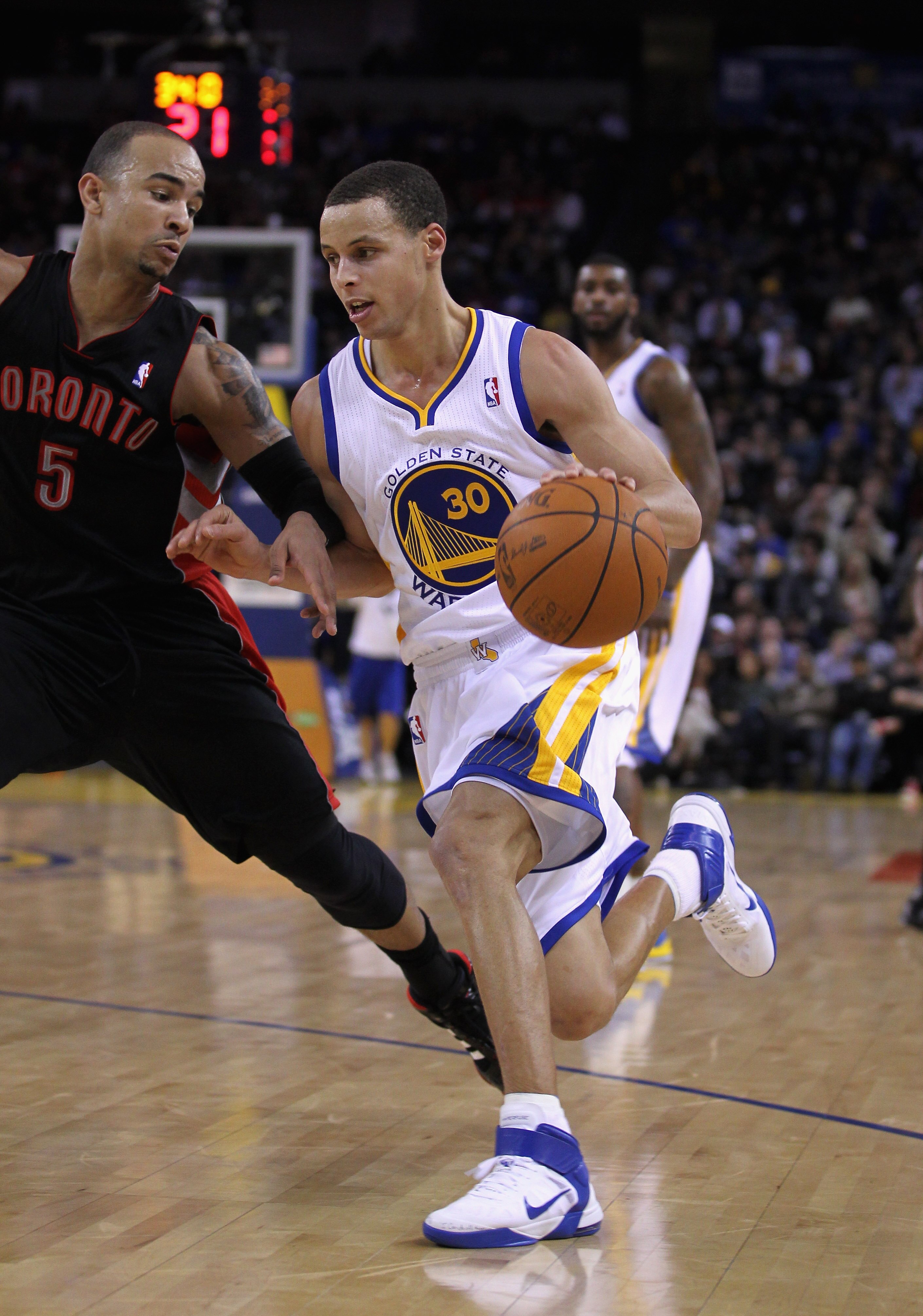 OAKLAND, CA - MARCH 25: Stephen Curry #30 of the Golden State Warriors drives on Jerryd Bayless #5 of the Toronto Raptors at Oracle Arena on March 25, 2011 in Oakland, California. NOTE TO USER: User expressly acknowledges and agrees that, by downloading a