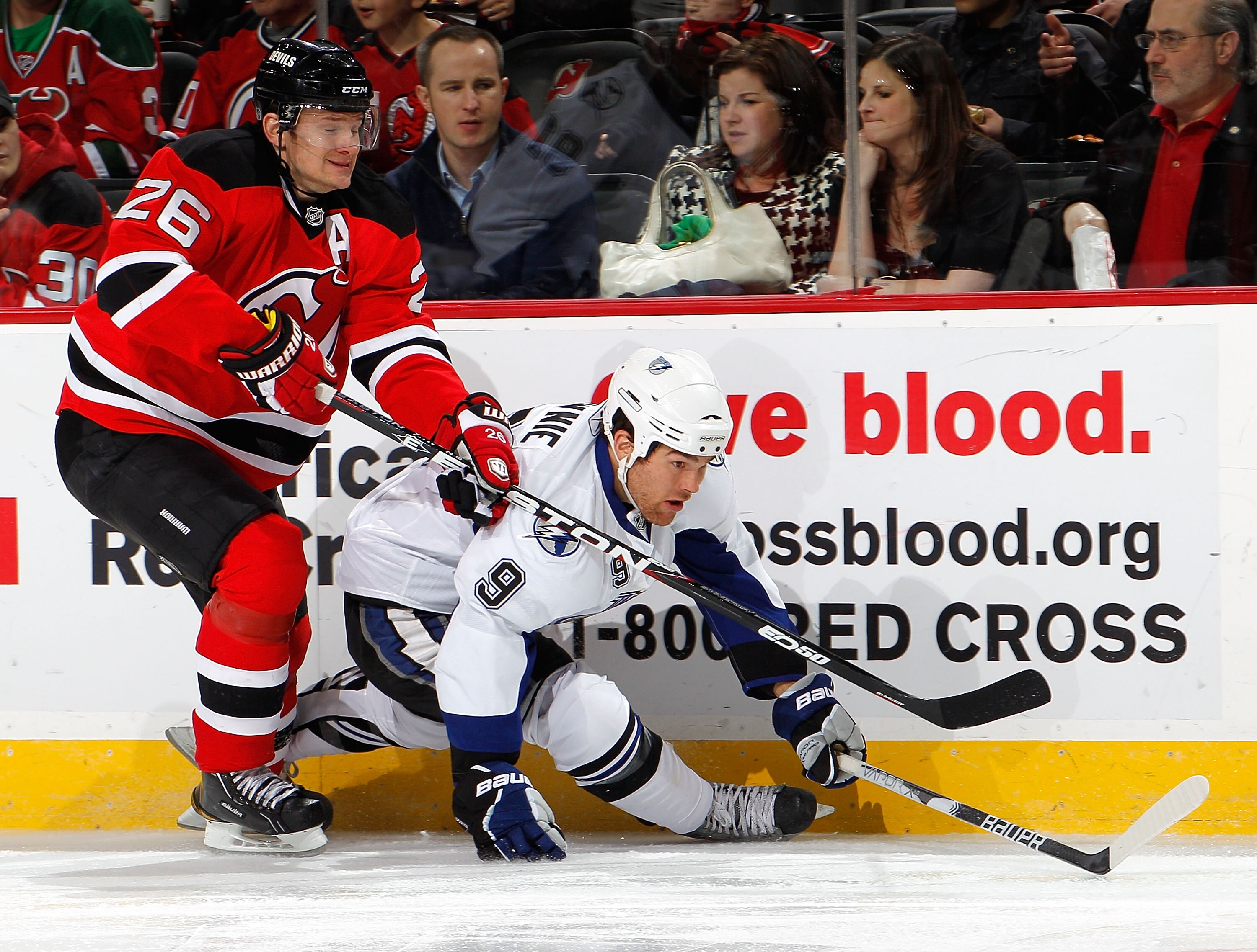 NEWARK, NJ - MARCH 02:  Patrik Elias #26 of the New Jersey Devils checks Steve Downie #9 of the Tampa Bay Lightning during the first period of an NHL hockey game at the Prudential Center on March 2, 2011 in Newark, New Jersey. Devils won 2-1. (Photo by Pa