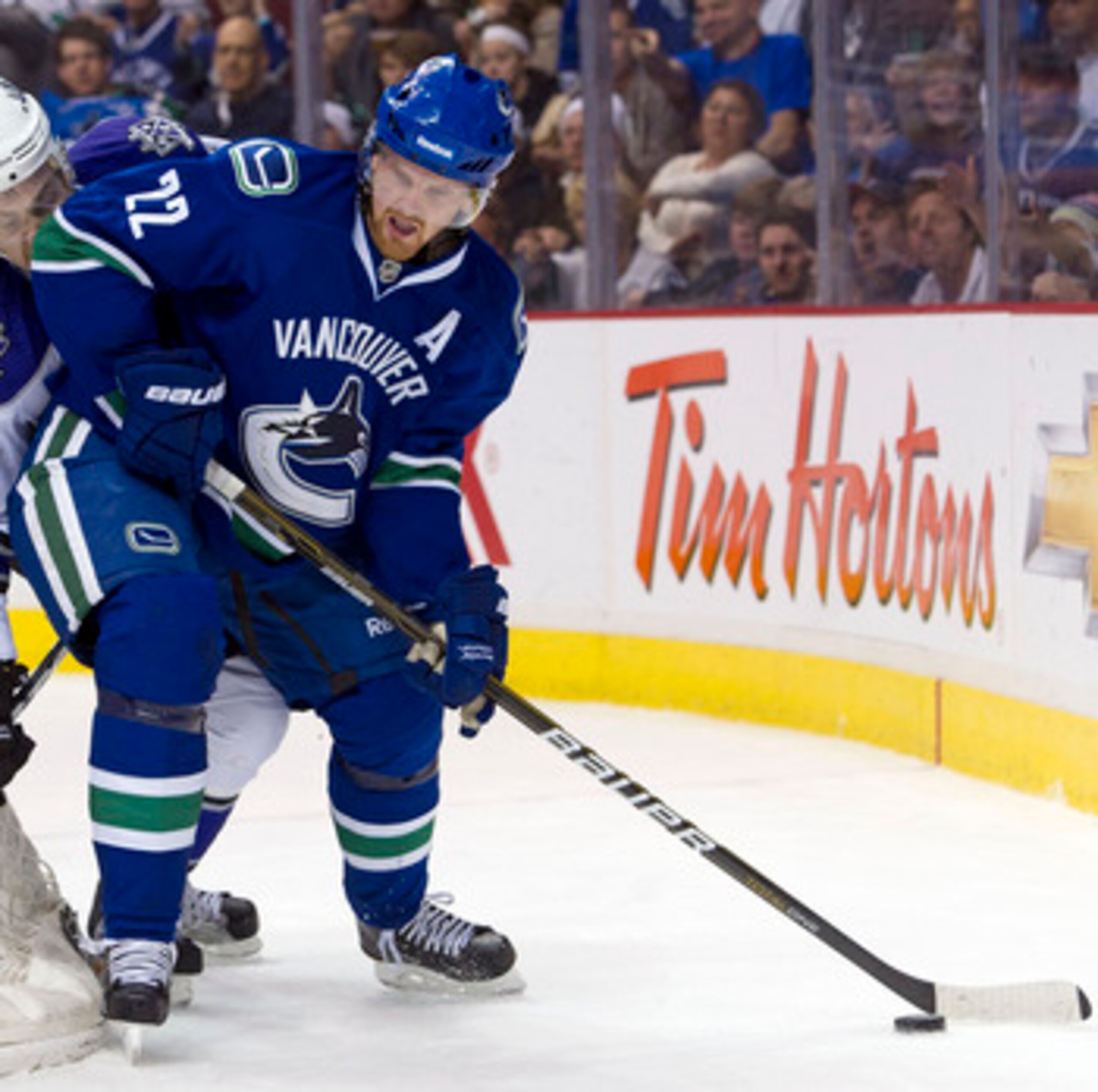 VANCOUVER, CANADA - MARCH 31: Daniel Sedin #22 of the Vancouver Canucks tries to fight off the check of Trevor Lewis #22 of the Los Angeles Kings during the second period in NHL action on March 31, 2011 at Rogers Arena in Vancouver, BC, Canada.  (Photo by