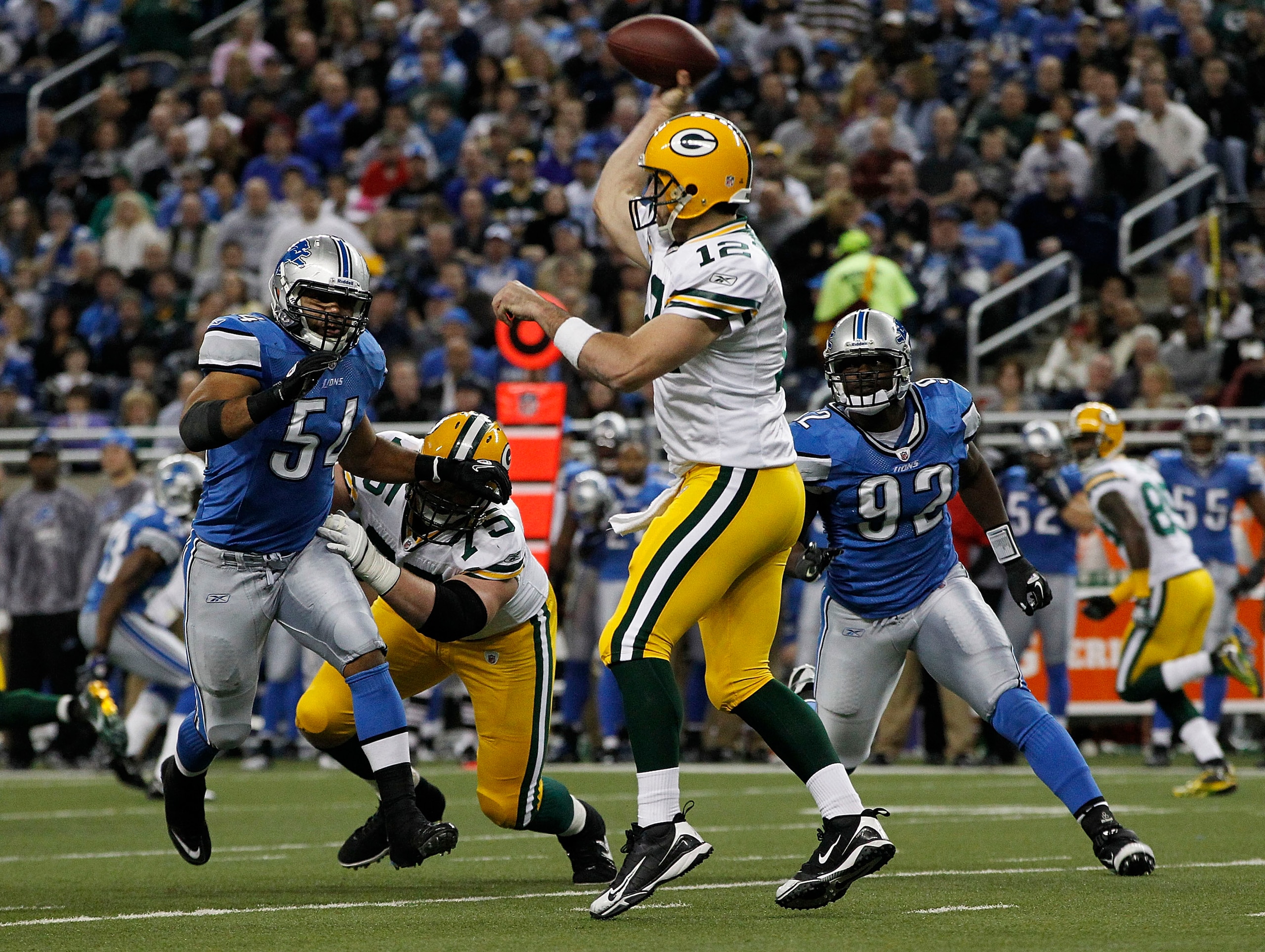 DETROIT - DECEMBER 12: Aaron Rogers #12 of the Green Bay Packers drops back to pass as DeAndre Levy #54 and Cliff Avrill #92 of the Detroit Lions rush the passer during the second quarter of the game against the Detroit Lions at Ford Field on December 12,