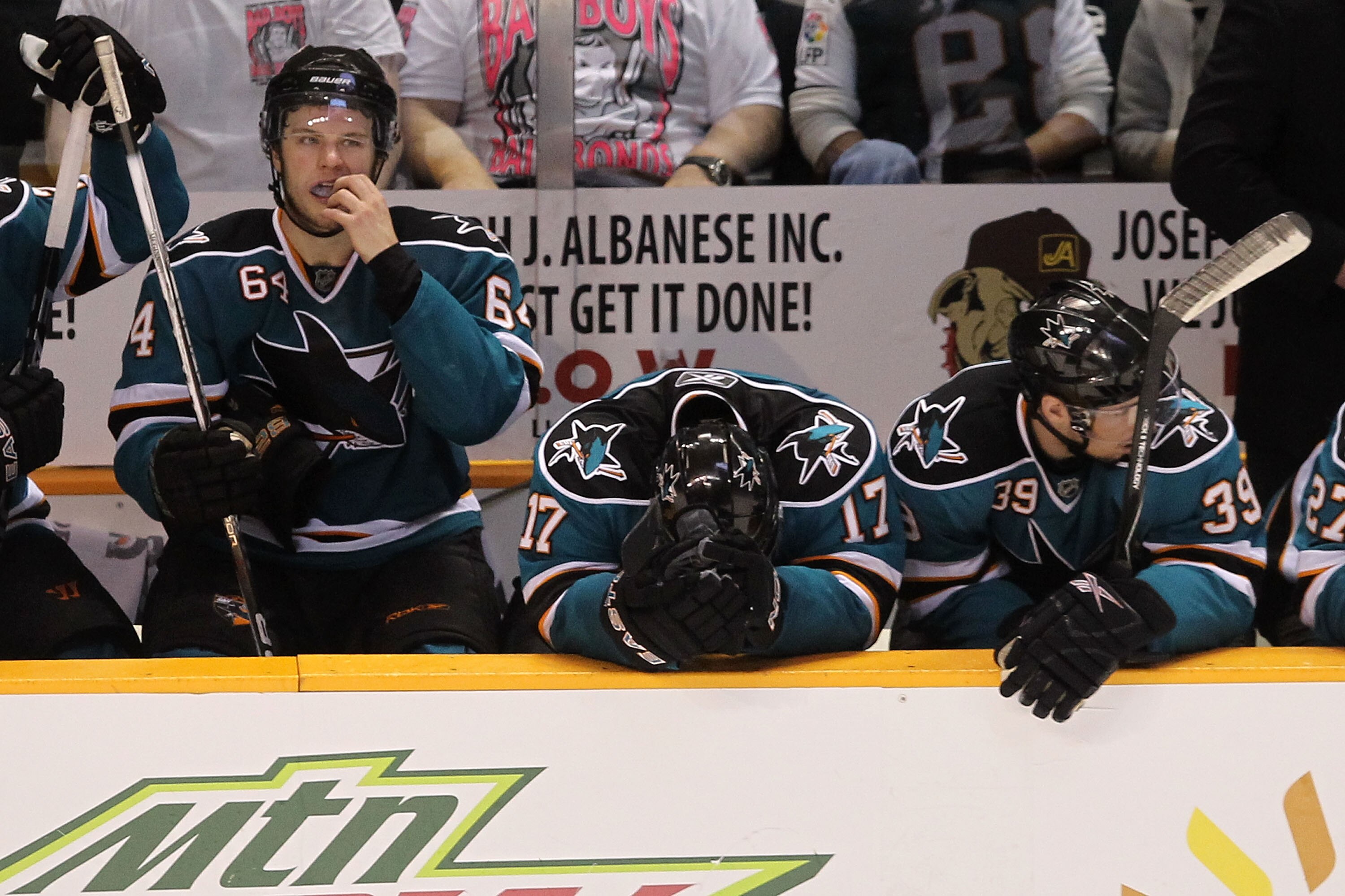 SAN JOSE, CA - MAY 18:  (L-R) Jamie McGinn #64, Torrey Mitchell #17 and Logan Couture #39 of the San Jose Sharks on the bench late in the fourth period before losing to the Chicago Blackhawks 4-2 in Game Two of the Western Conference Finals during the 201