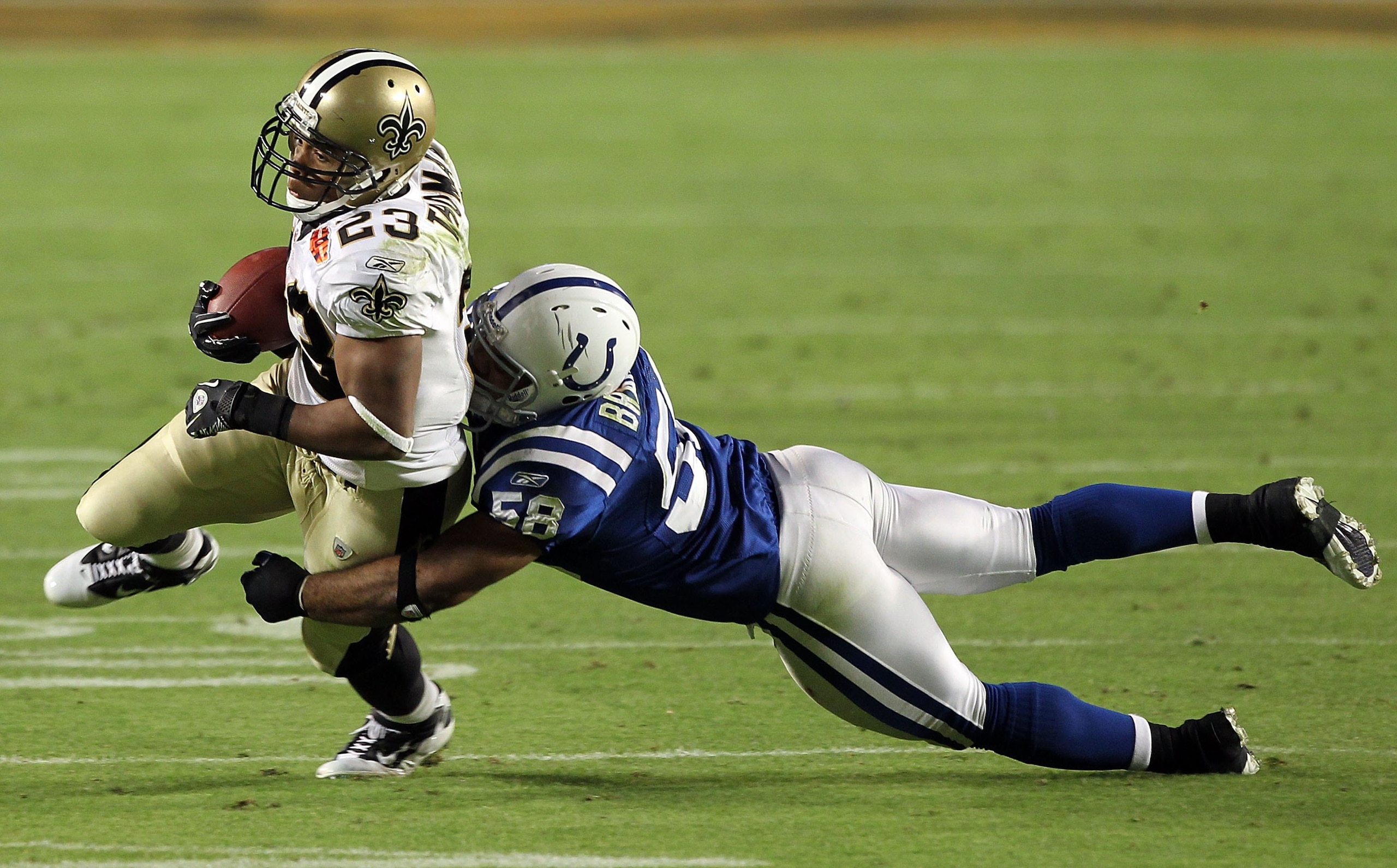 MIAMI GARDENS, FL - FEBRUARY 07:   Gary Brackett #58 of the Indianapolis Colts tackles Pierre Thomas #23 of the New Orleans Saints on fourth and goal during Super Bowl XLIV on February 7, 2010 at Sun Life Stadium in Miami Gardens, Florida.  (Photo by Ezra