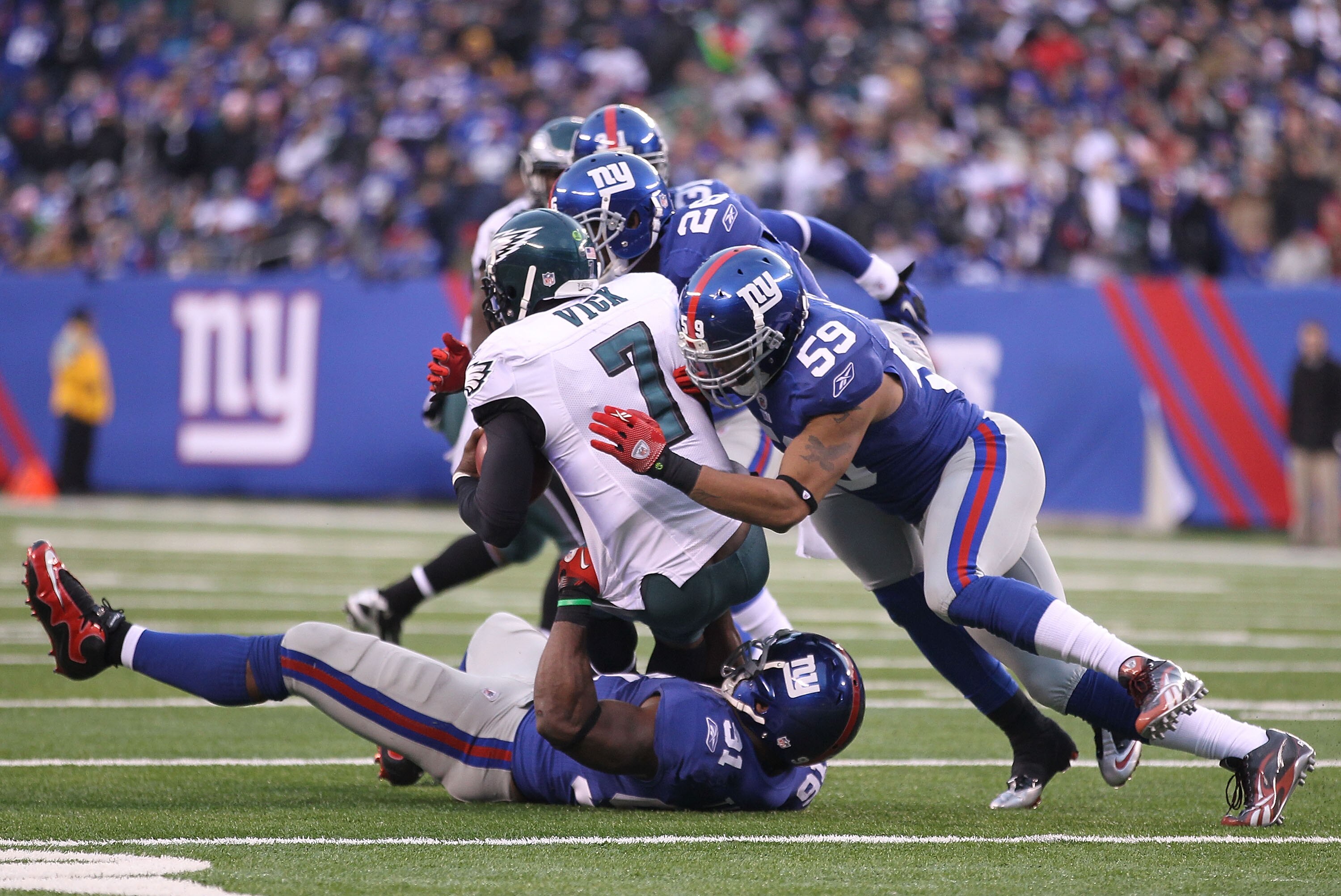 EAST RUTHERFORD, NJ - DECEMBER 19:  Justin Tuck #91, Michael Boley #59, and Antrel Rolle #26 of the New York Giants tackle Michael Vick #7 of the Philadelphia Eagles during their game on December 19, 2010 at The New Meadowlands Stadium in East Rutherford,