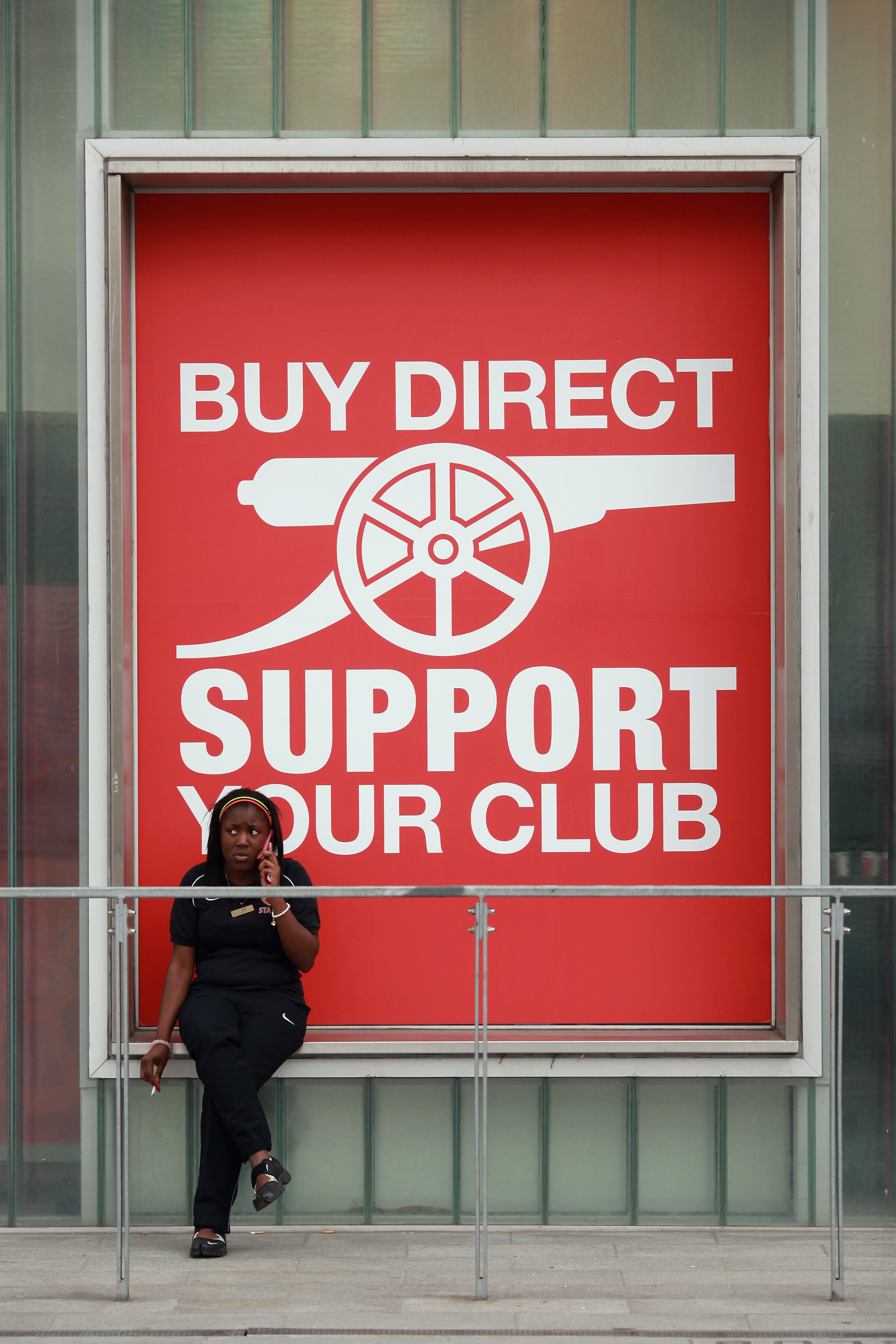 LONDON, ENGLAND - APRIL 11:  A woman sits in front of the club shop at Arsenal Football Club's Emirates Stadium on April 11, 2011 in London, England. American businessman Stan Kroenke's company 'Kroenke Sports Enterprises' has increased its shareholding i