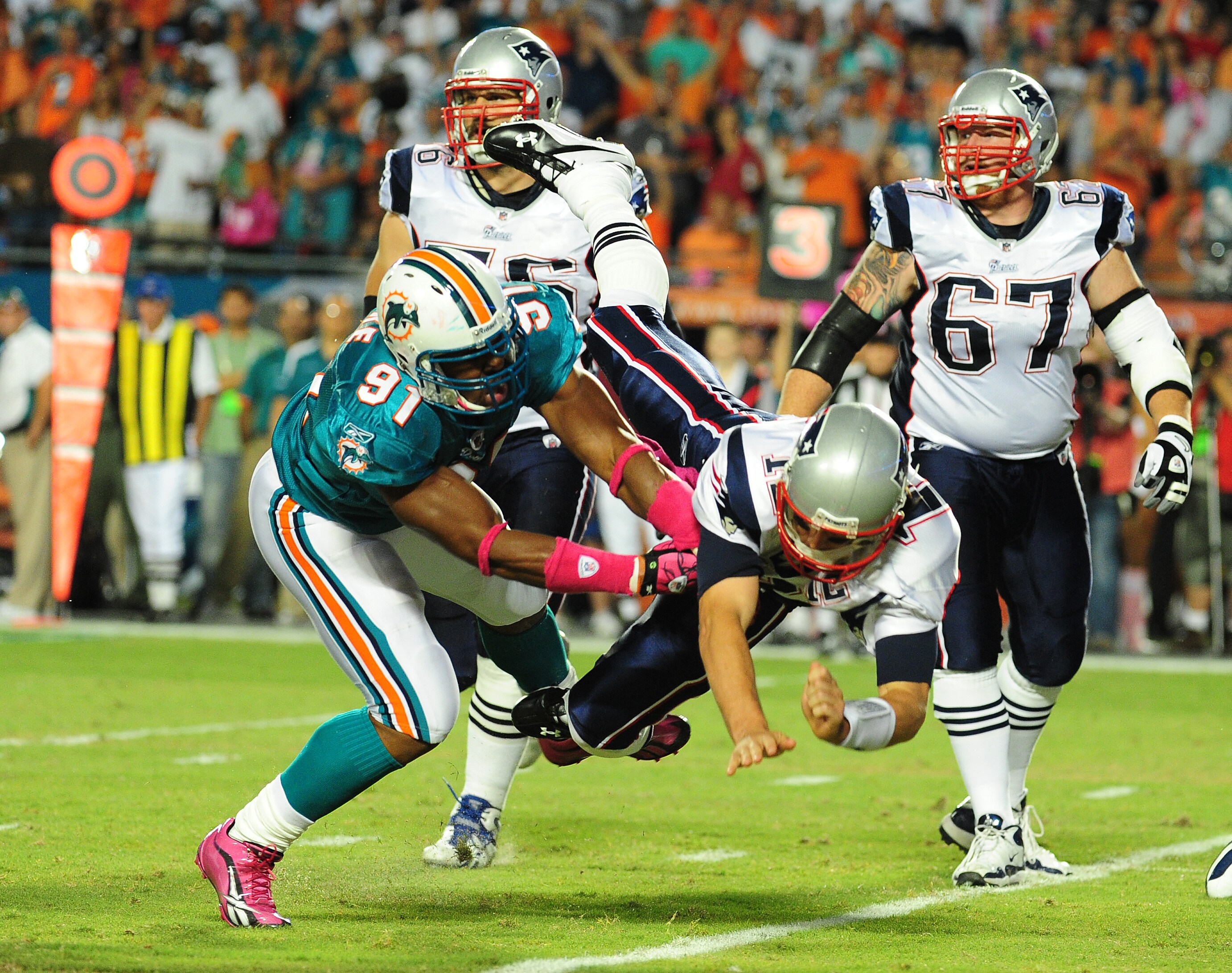 MIAMI - OCTOBER 4: Tom Brady #12 of the New England Patriots is hit after he passes by Cameron Wake #91 of the Miami Dolphins at Sun Life Field on October 4, 2010 in Miami, Florida. (Photo by Scott Cunningham/Getty Images)