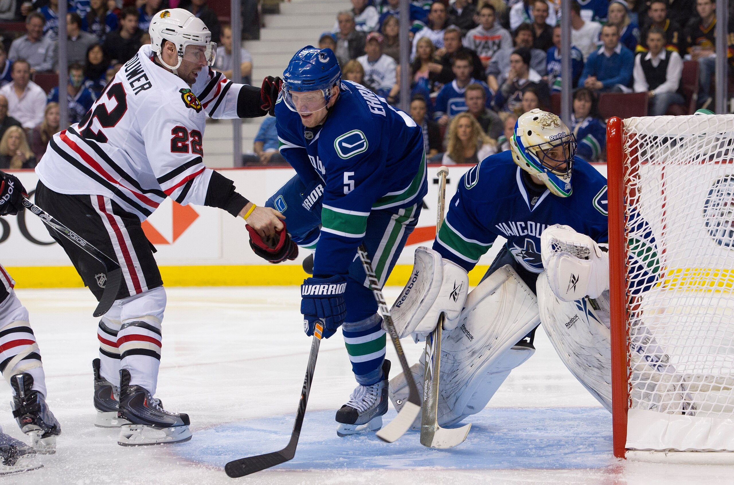 VANCOUVER, CANADA - APRIL 13: Goalie Roberto Luongo #1 of the Vancouver Canucks keeps an eye on the play while Troy Brouwer #22 of the Chicago Blackhawks and Christian Ehrhoff #5 of the Canucks battle for position during the third period in Game One of th