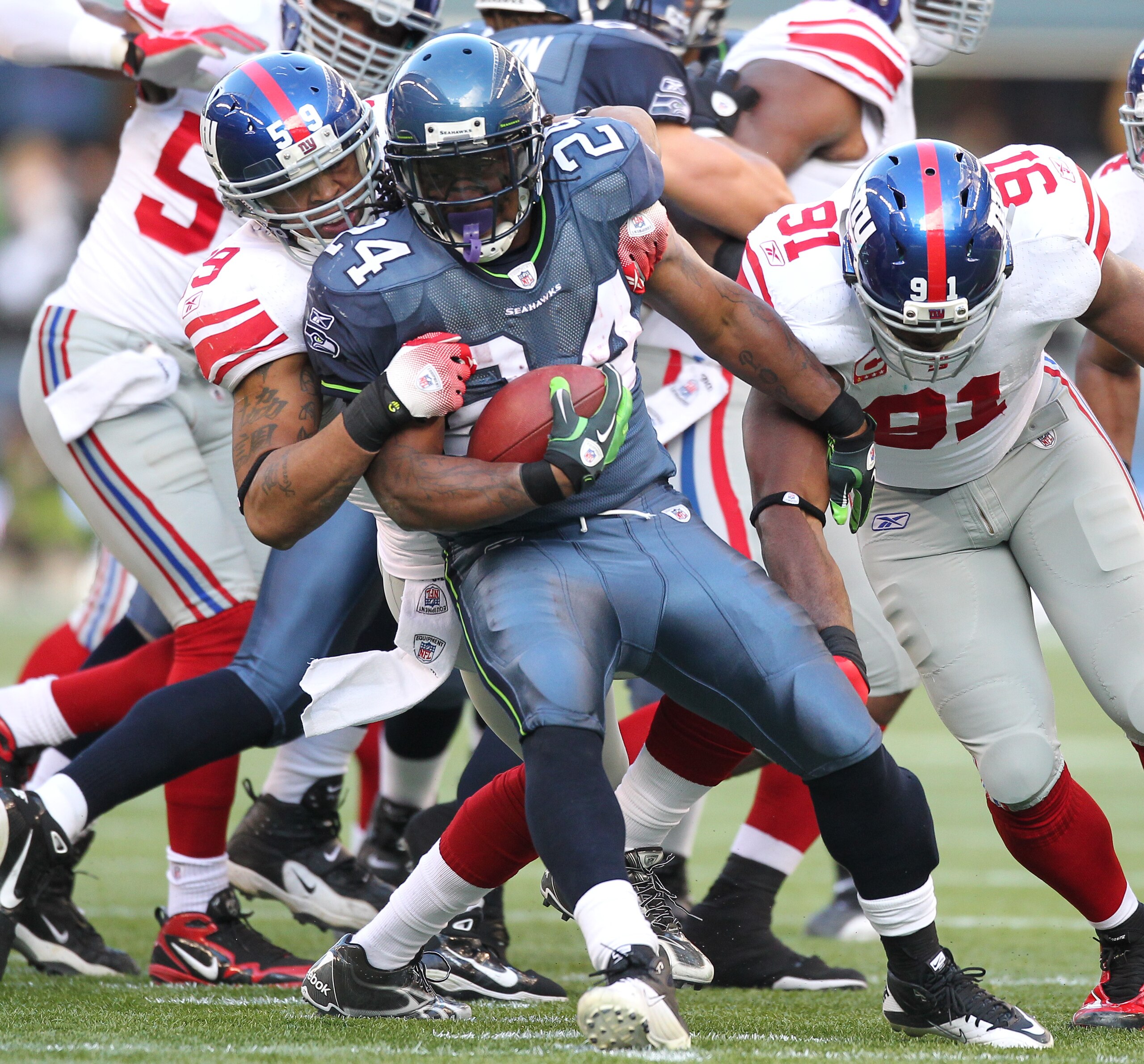 SEATTLE - NOVEMBER 07:  Running back Marshawn Lynch #24 of the Seattle Seahawks is tackled by Michael Boley #59 and defensive end Justin Tuck #91 of the New York Giants at Qwest Field on November 7, 2010 in Seattle, Washington. The Giants defeated the Sea