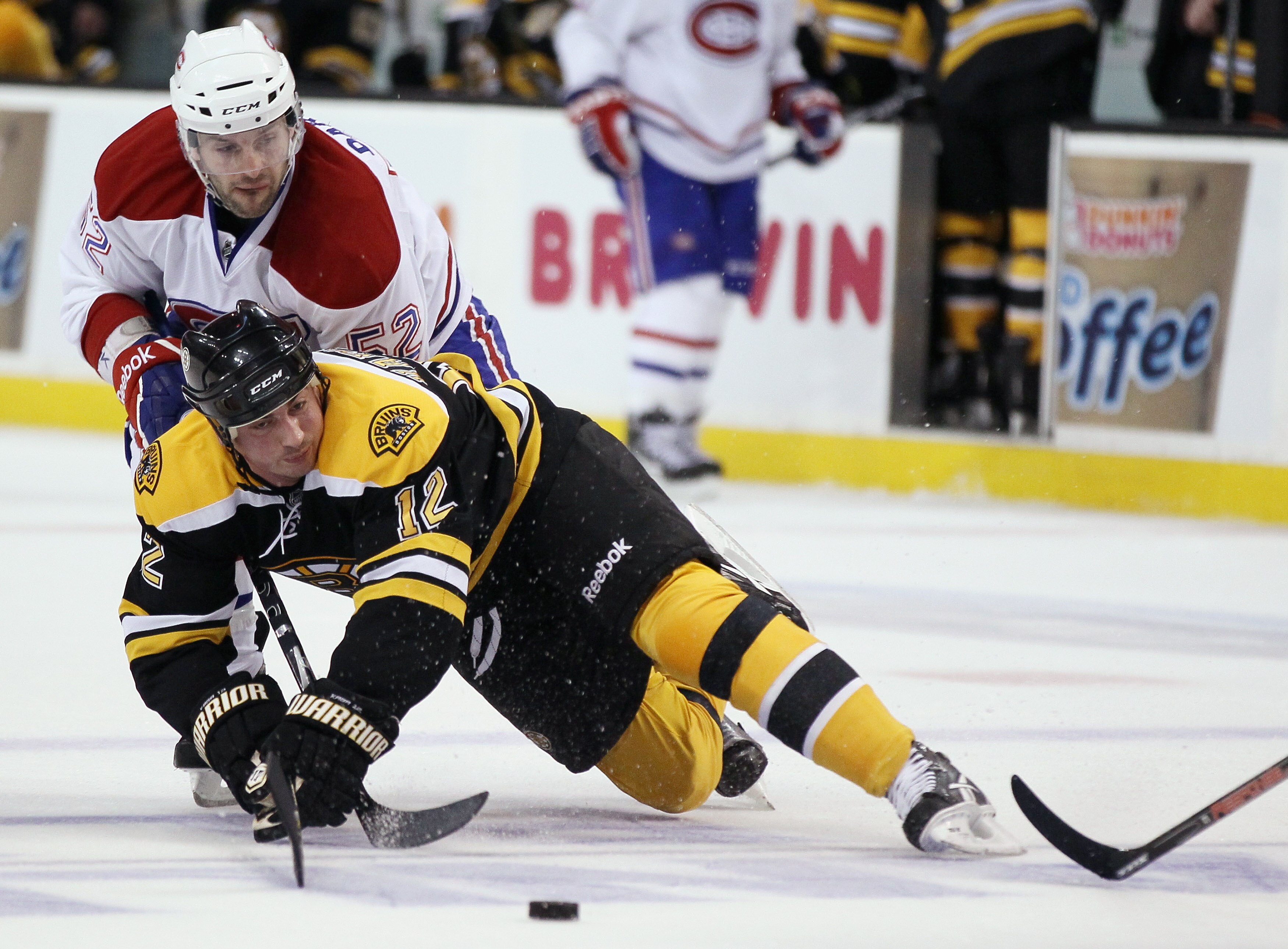 BOSTON, MA - APRIL 16:  Tomas Kaberle #12 of the Boston Bruins is shoved by Mathieu Darche #52 of the Montreal Canadiens in Game Two of the Eastern Conference Quarterfinals during the 2011 NHL Stanley Cup Playoffs at TD Garden on April 16, 2011 in Boston,