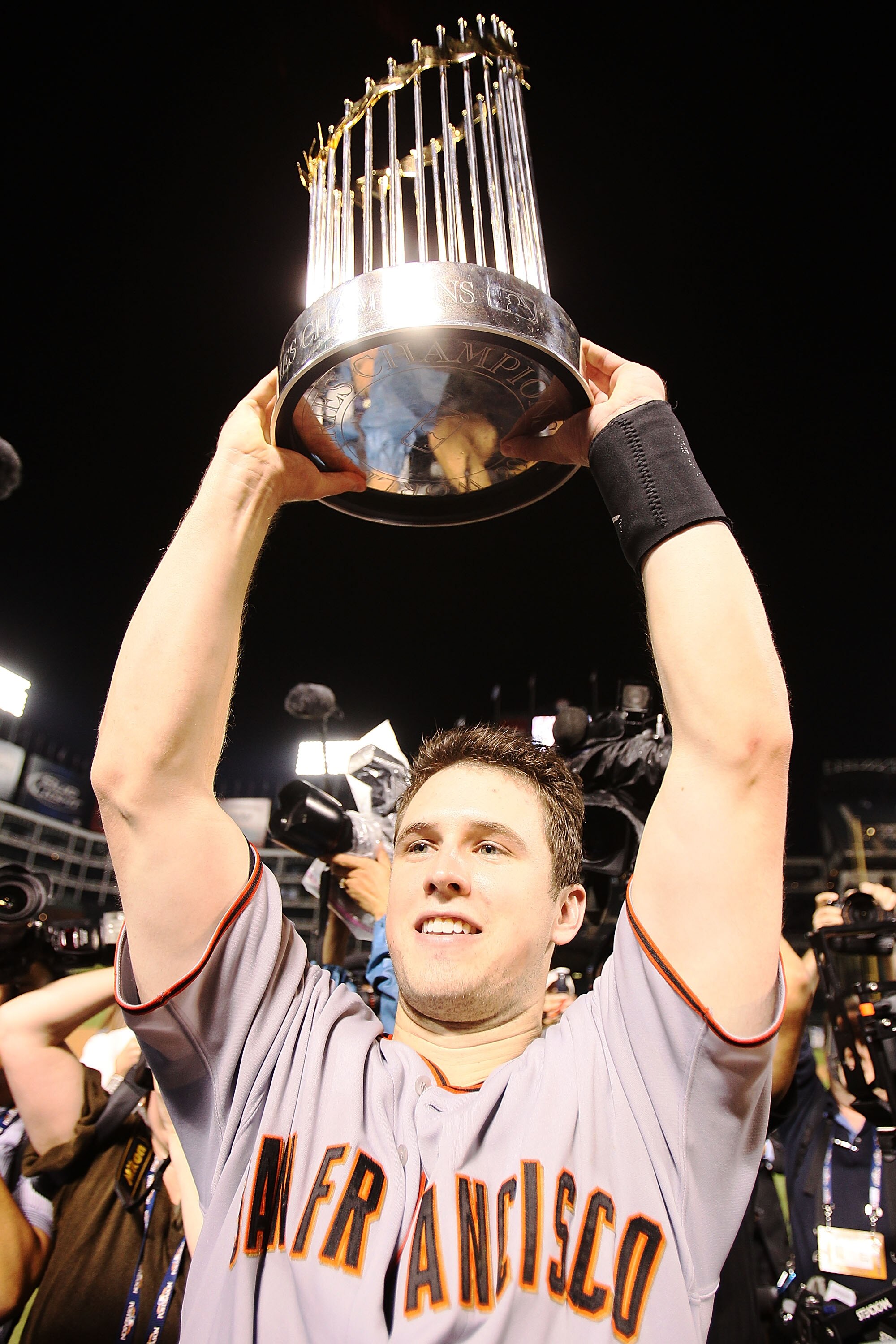 ARLINGTON, TX - NOVEMBER 01:  Buster Posey #28 of the San Francisco Giants celebrates with the World Series Championship trophy after the Giants won 3-1 the Texas Rangers in Game Five of the 2010 MLB World Series at Rangers Ballpark in Arlington on Novemb