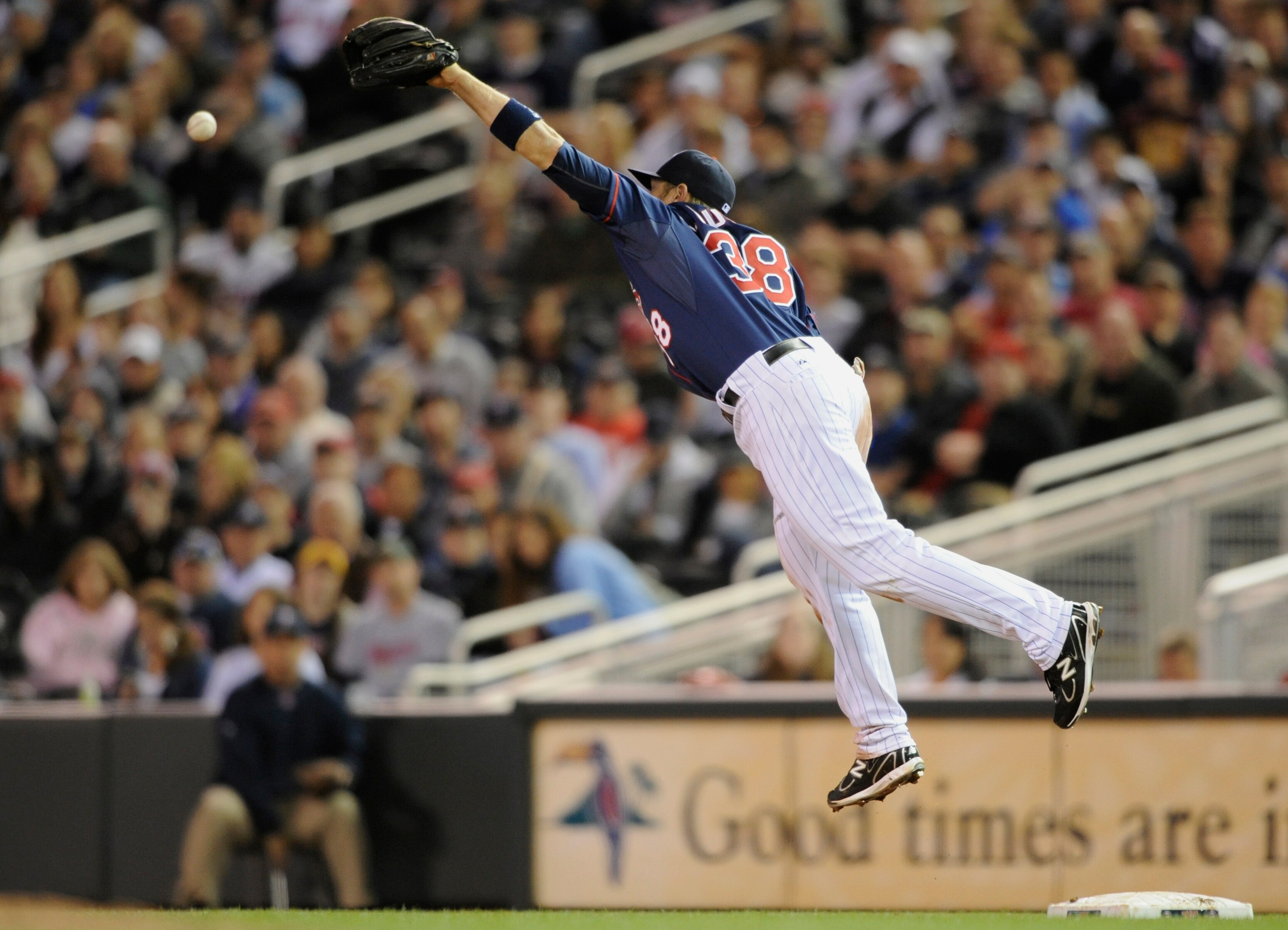 MINNEAPOLIS, MN - APRIL 12: Luke Hughes #38 of the Minnesota Twins leaps in the air in an attempt to catch a throwing error by Brian Duensing #52 against the Kansas City Royals during the seventh inning of their game on April 12, 2011 at Target Field in M
