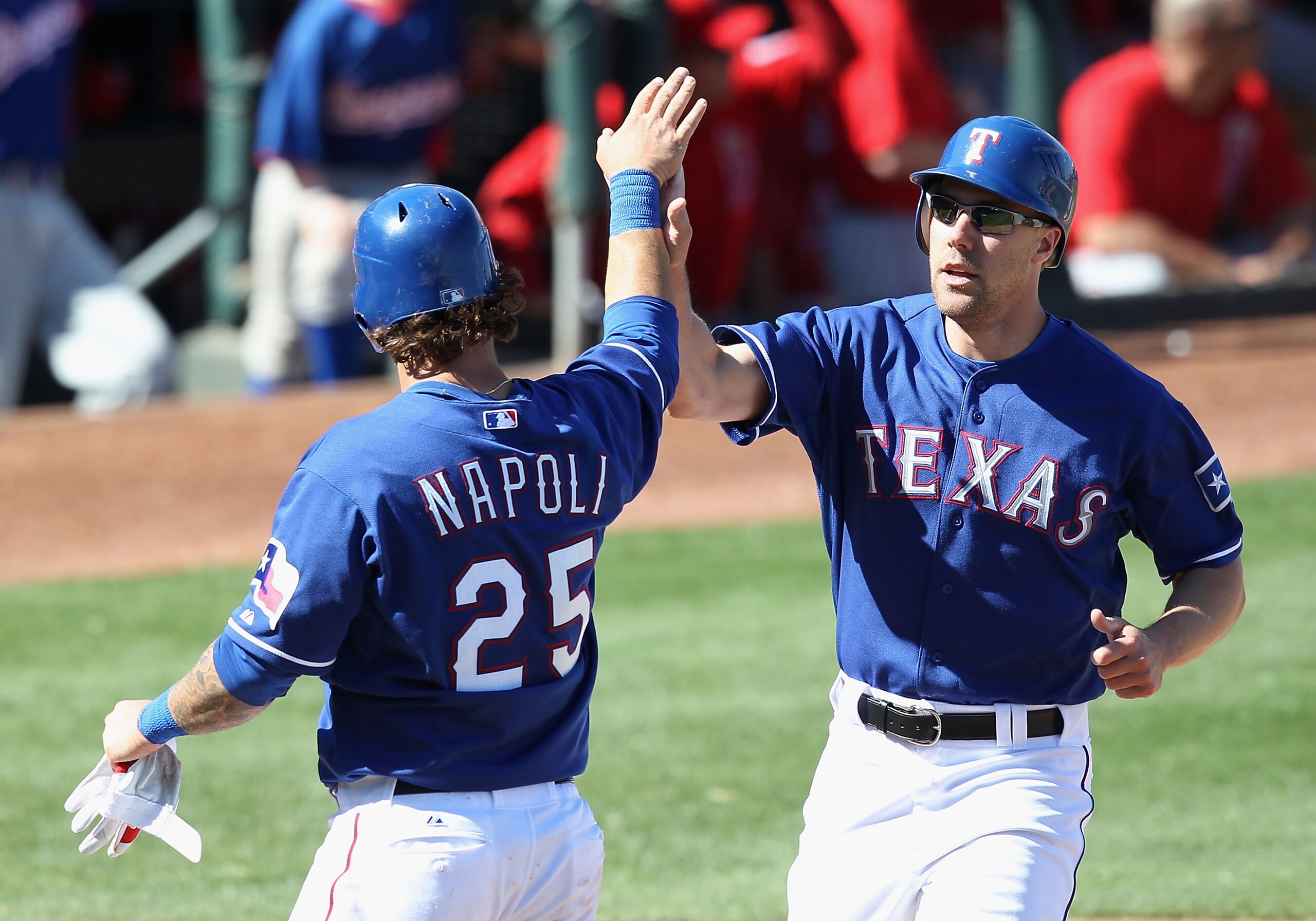 SURPRISE, AZ - MARCH 02:  David Murphy #7 of the Texas Rangers high fives teammate Mike Napoli #25 after they both scored on a RBI double by Jose Ruiz (not pictured) during the fourth inning of the spring training game against the Los Angeles Angels of An