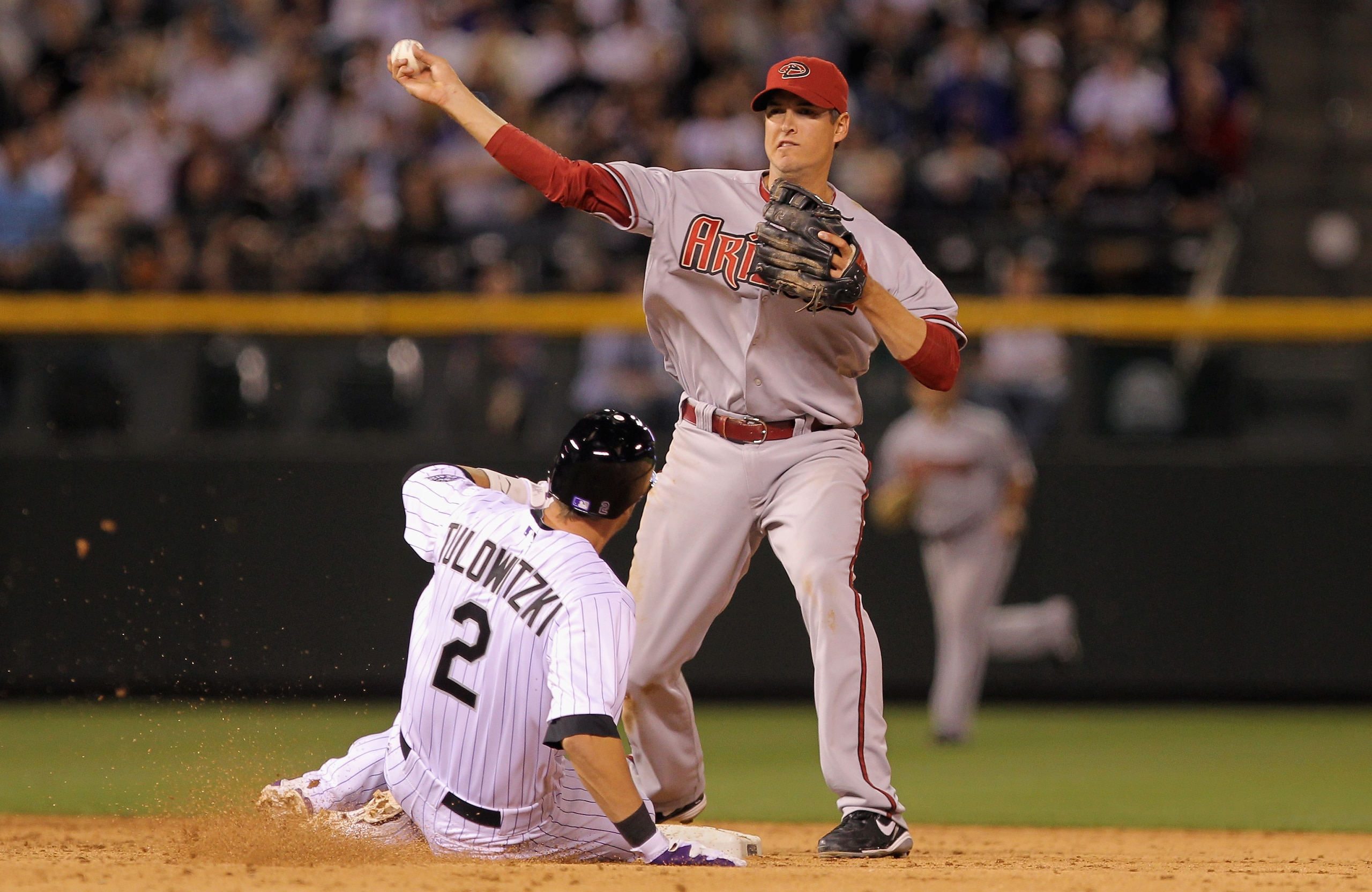 DENVER, CO - APRIL 02:  Second baseman Kelly Johnson #2 of the Arizona Diamondbacks turns a double play on Troy Tulowitzki #2 of the Colorado Rockies on a grounder by Todd Helton of the Rockies to end the eighth inning at Coors Field on April 2, 2011 in D
